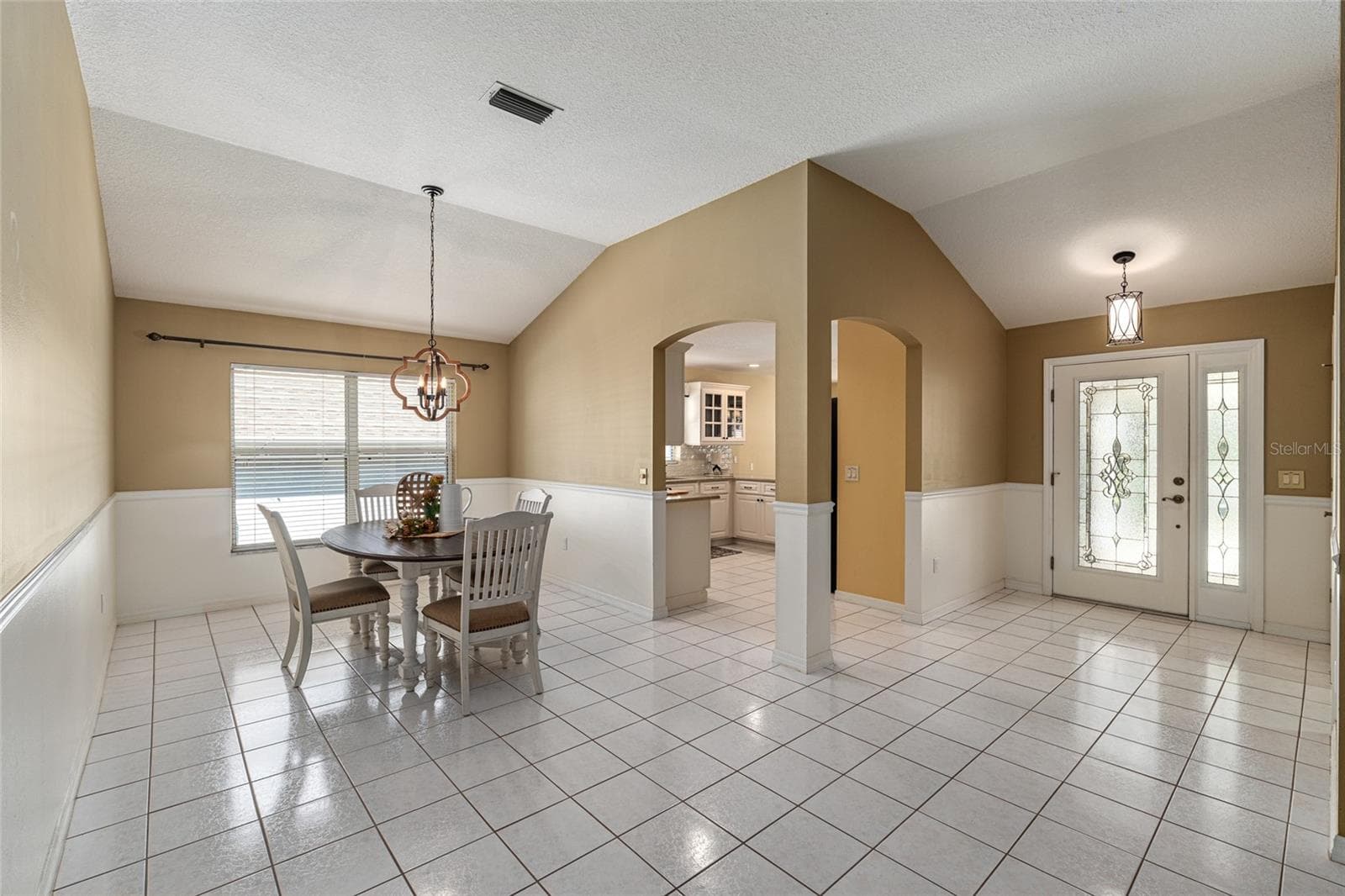 Dining Area: Dedicated dining space with tile flooring, chair rail detail, and a stylish light fixture for everyday meals or gatherings. - 110 CHULA VISTA AVE, LADY LAKE