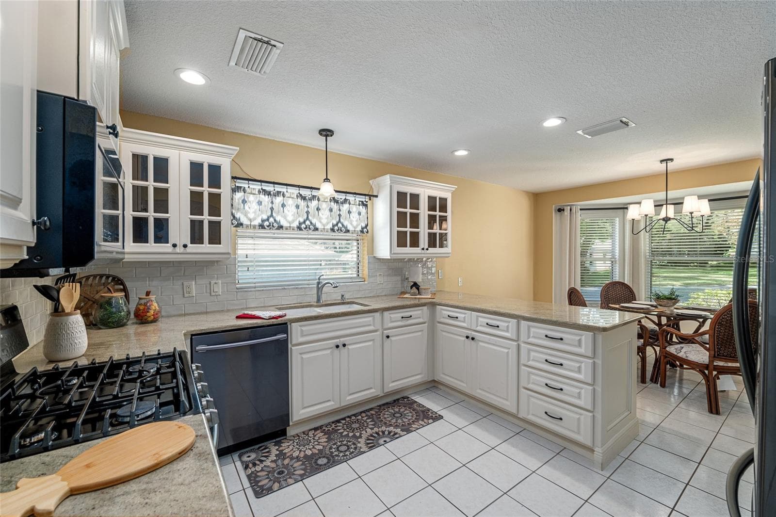 Kitchen: Well-appointed kitchen features granite countertops, white cabinetry, and stainless steel appliances for a clean, functional design. - 110 CHULA VISTA AVE, LADY LAKE