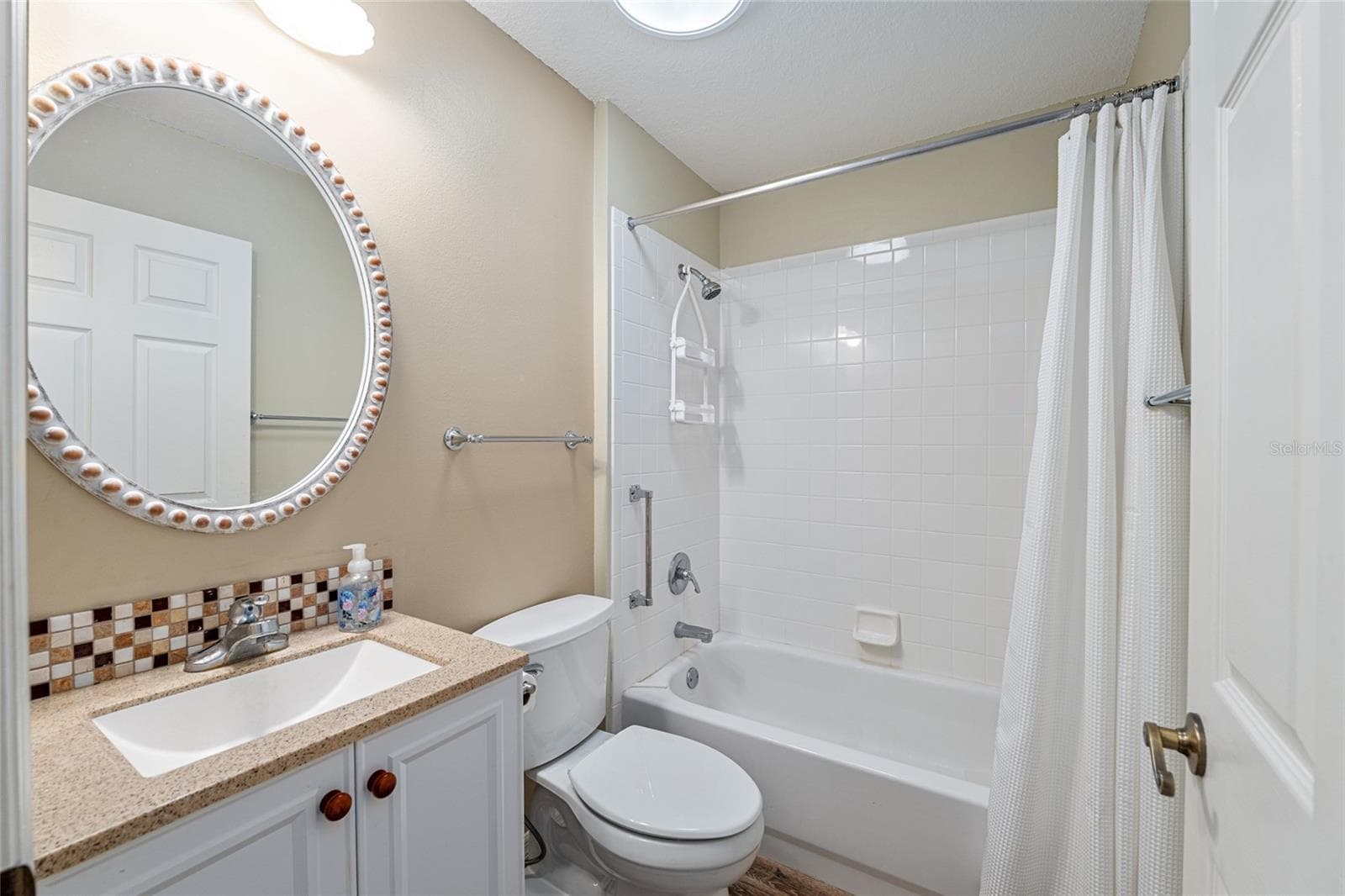 Guest Bathroom: Guest bathroom includes a single-sink vanity, tiled tub/shower combination, and neutral finishes. - 110 CHULA VISTA AVE, LADY LAKE