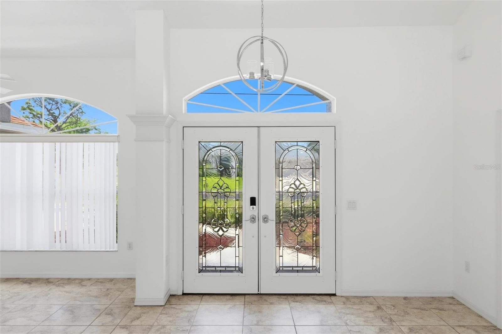 Elegant foyer with arched transom window, double doors, and decorative tile floors - 605 ROTONDA CIR, ROTONDA WEST