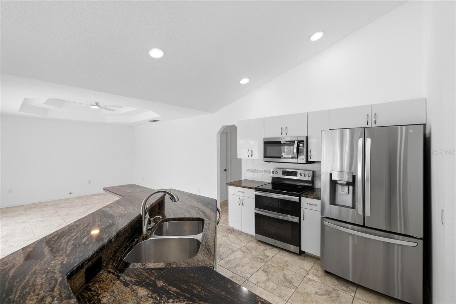 Modern kitchen featuring all-new 2024 appliances, dark countertops, and island seating - 605 ROTONDA CIR, ROTONDA WEST