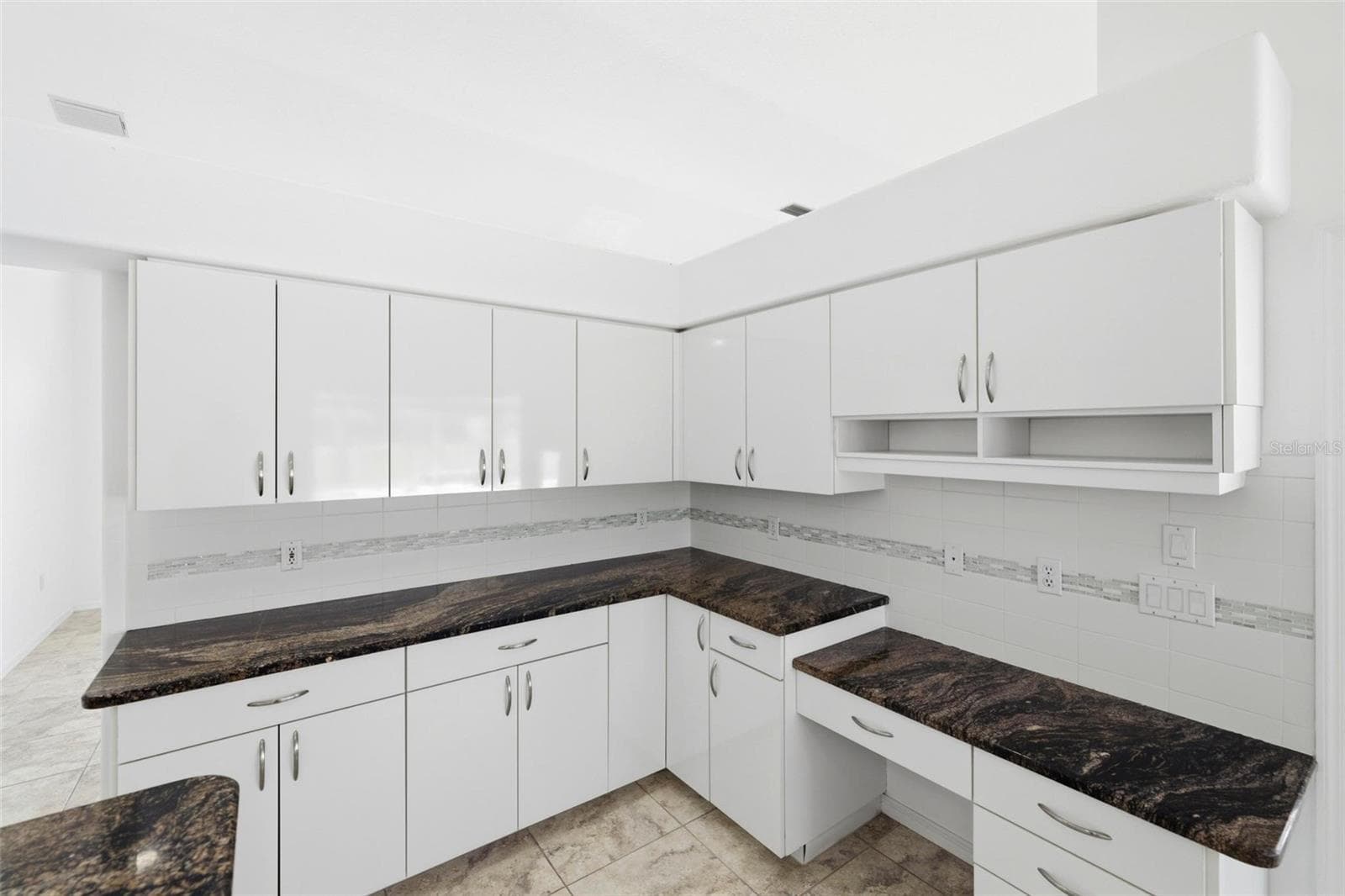 Large kitchen with dark granite countertops, white cabinets, and new 2024 range - 605 ROTONDA CIR, ROTONDA WEST