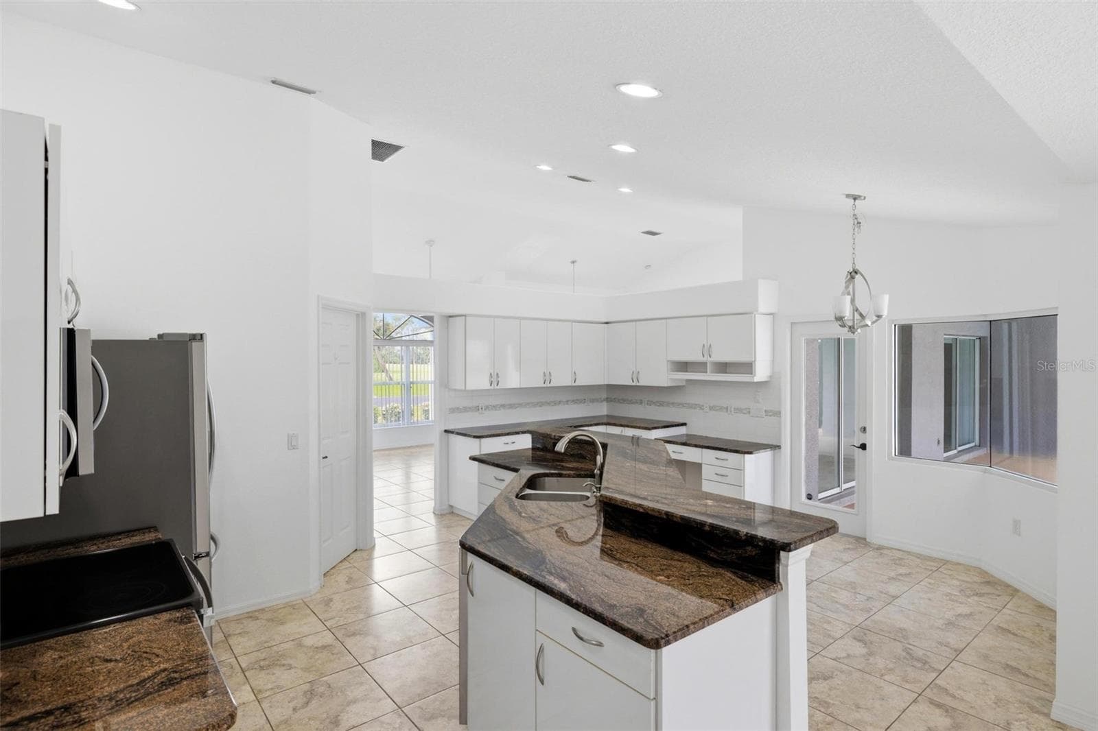 Spacious kitchen with island, dark granite counters, and view into living area - 605 ROTONDA CIR, ROTONDA WEST