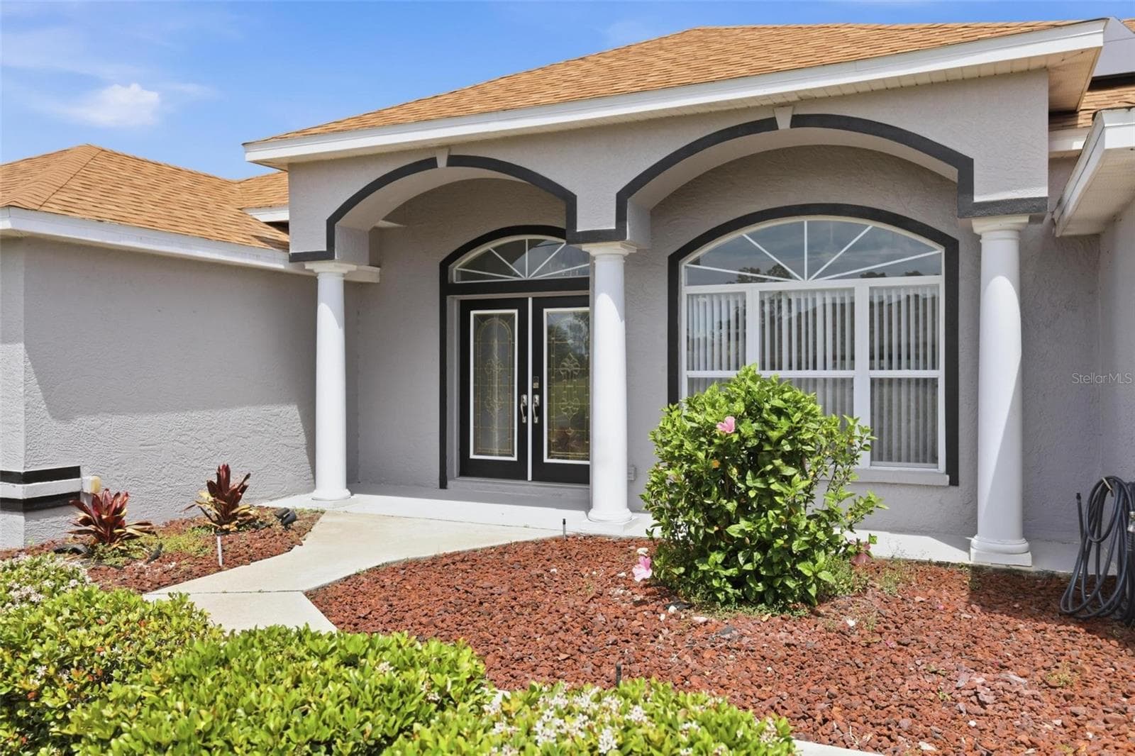 Elegant arched entry with lush tropical landscaping and excellent curb appeal - 605 ROTONDA CIR, ROTONDA WEST