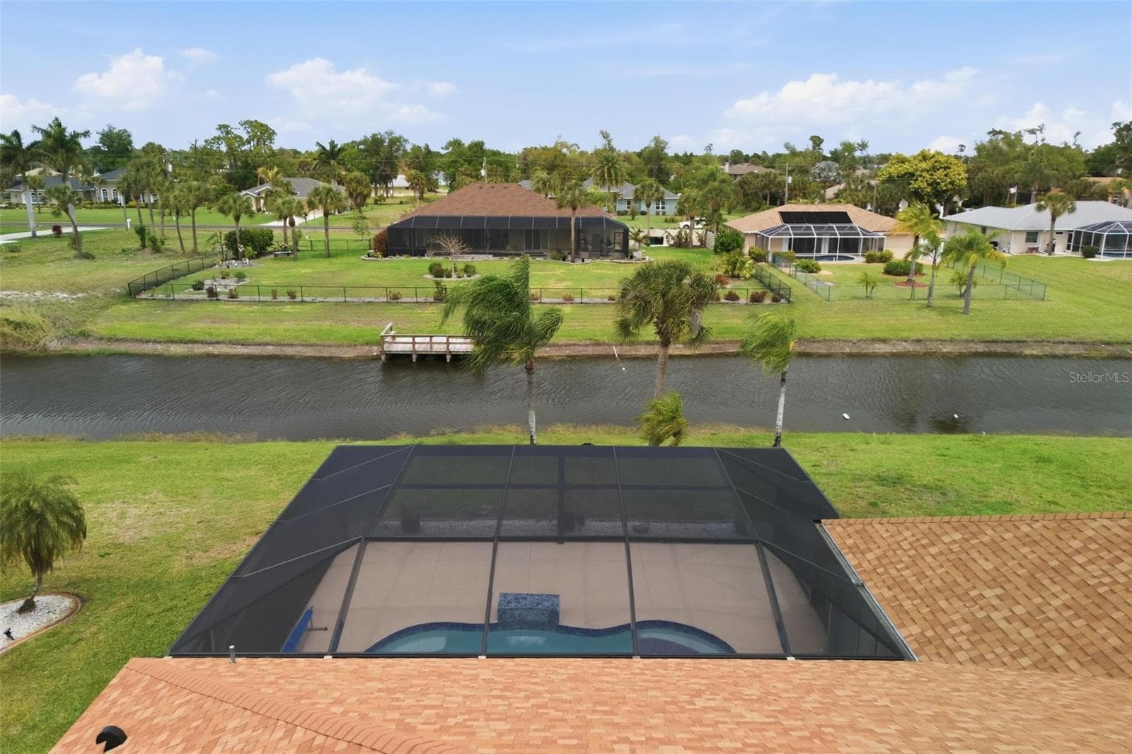 Aerial view highlighting panoramic screen enclosure, owned solar panels (2025), and lush lot - 605 ROTONDA CIR, ROTONDA WEST