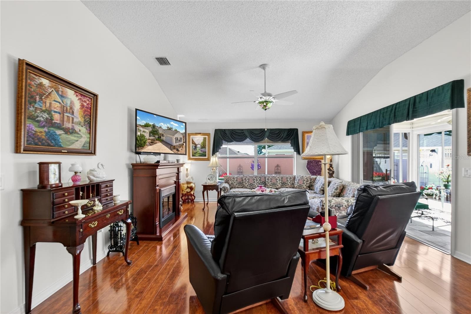 LIVING ROOM BOASTS VAULTED CEILING, ELECTRIC FIREPLACE, VIEWS OF THE TROPICAL GARDEN IN THE COURTYARD - 1147 ELIZABETH CT, THE VILLAGES