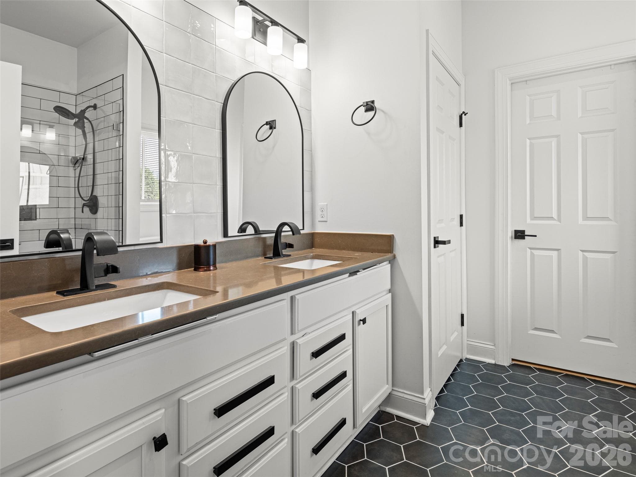Luxurious primary ensuite bath with all new details including tile flooring, mirrors, lighting, tile backsplash, and fixtures. Linen closet + large walk-in closet - 127 Rockbridge Road, Mills River