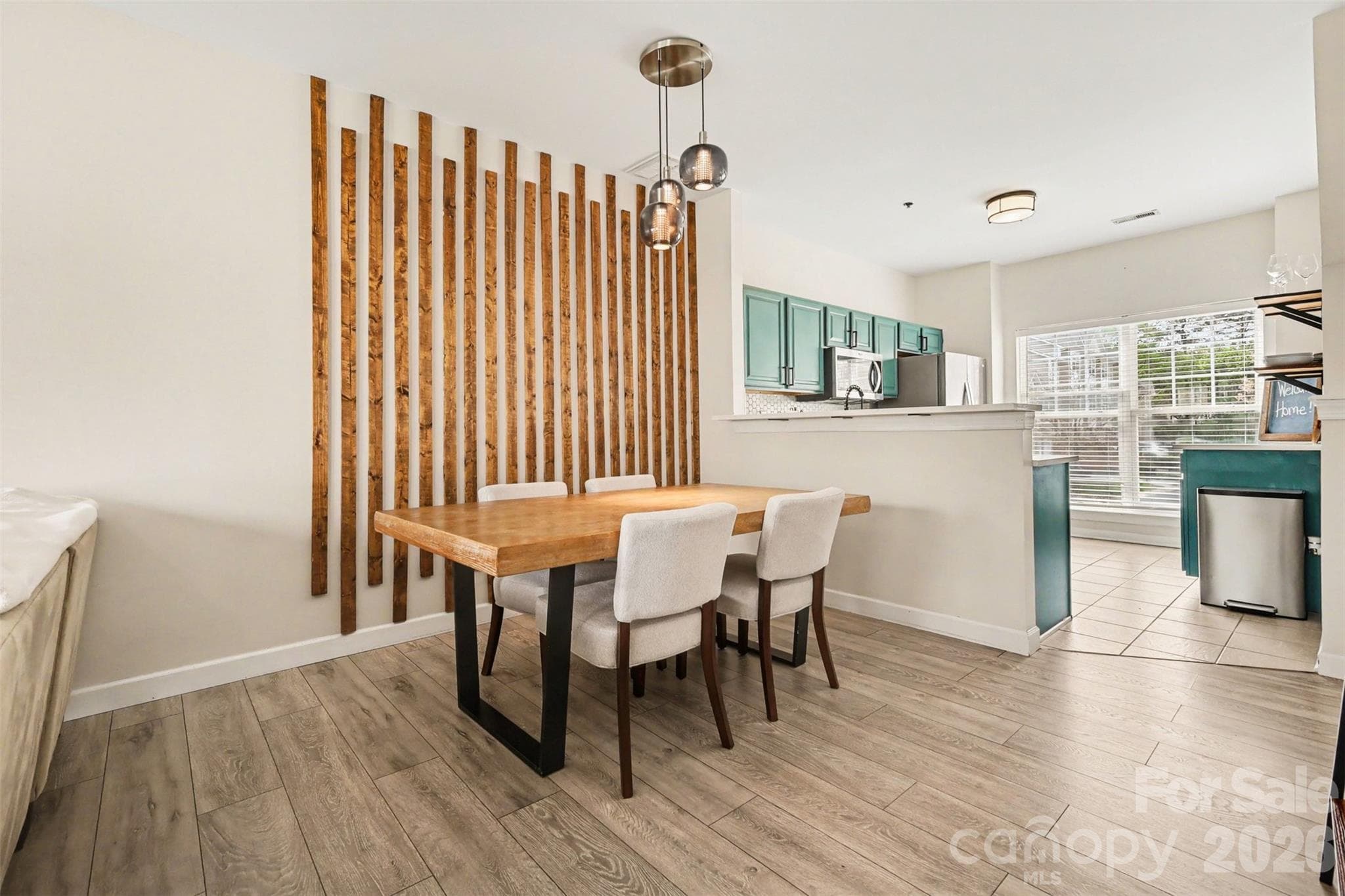 Open-concept dining and living space showcasing a custom wood accent wall and seamless flow for everyday living and entertaining. - 2729 Avalon Loop Road, Charlotte