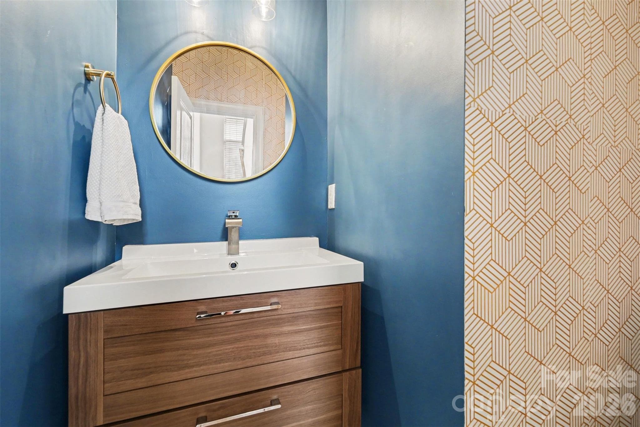 Convenient main-level half bath featuring a modern vanity, fresh paint, and a stylish geometric accent wall. - 2729 Avalon Loop Road, Charlotte