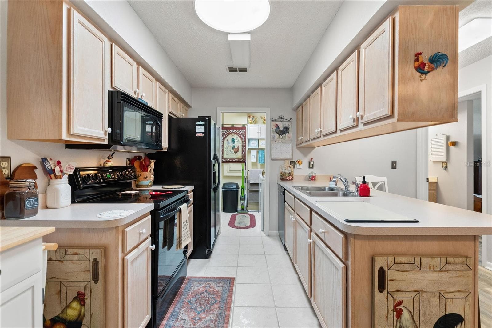 The galley-style kitchen has loads of cabinetry and counter space. The laundry room is conveniently located at the end of the kitchen - 302 GENESIS POINTE DR, LAKE WALES