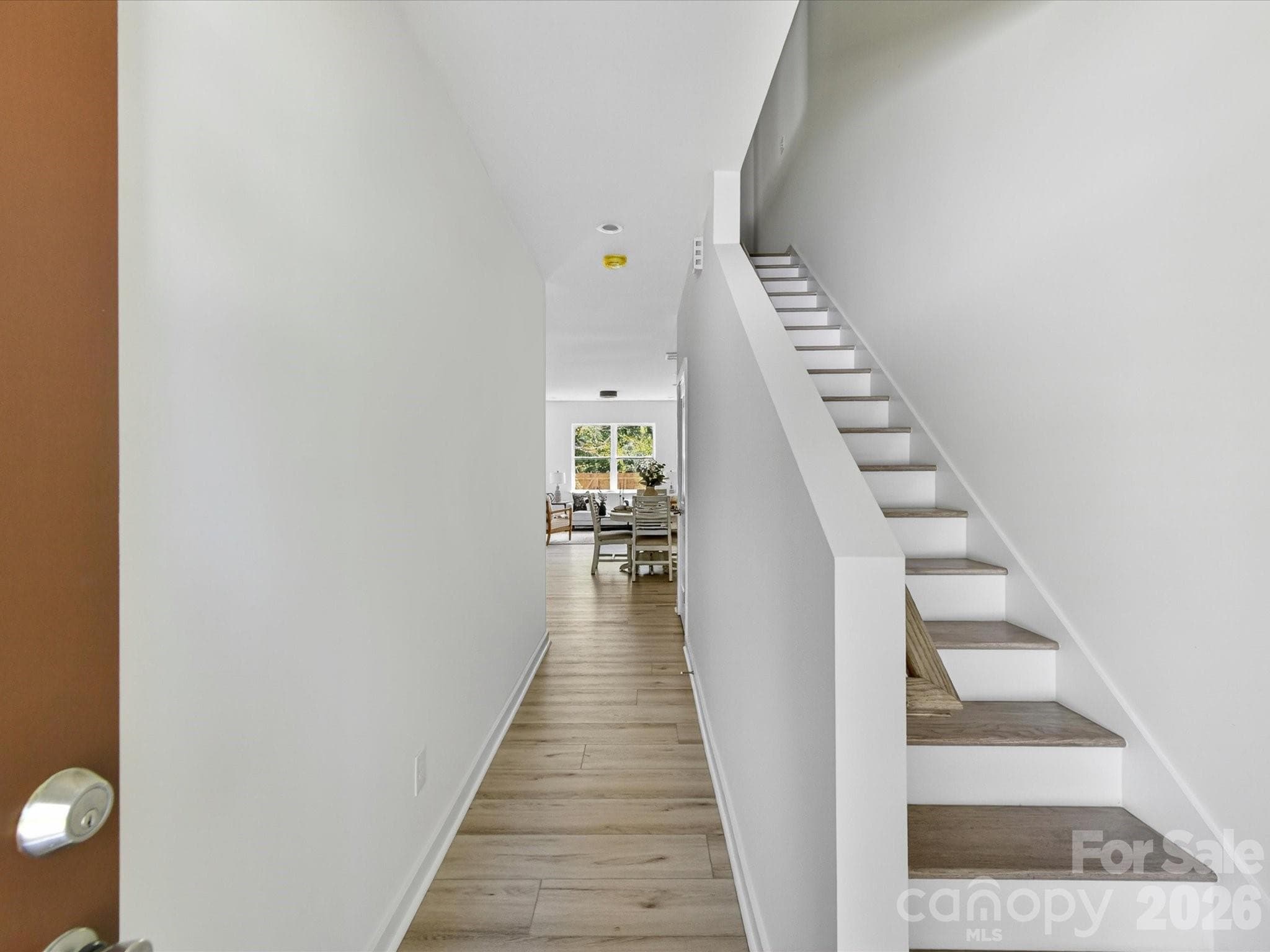 Bright and welcoming foyer featuring clean modern finishes, durable flooring, and a convenient staircase leading to the upper level. - 655 Stillgreen Lane, Charlotte