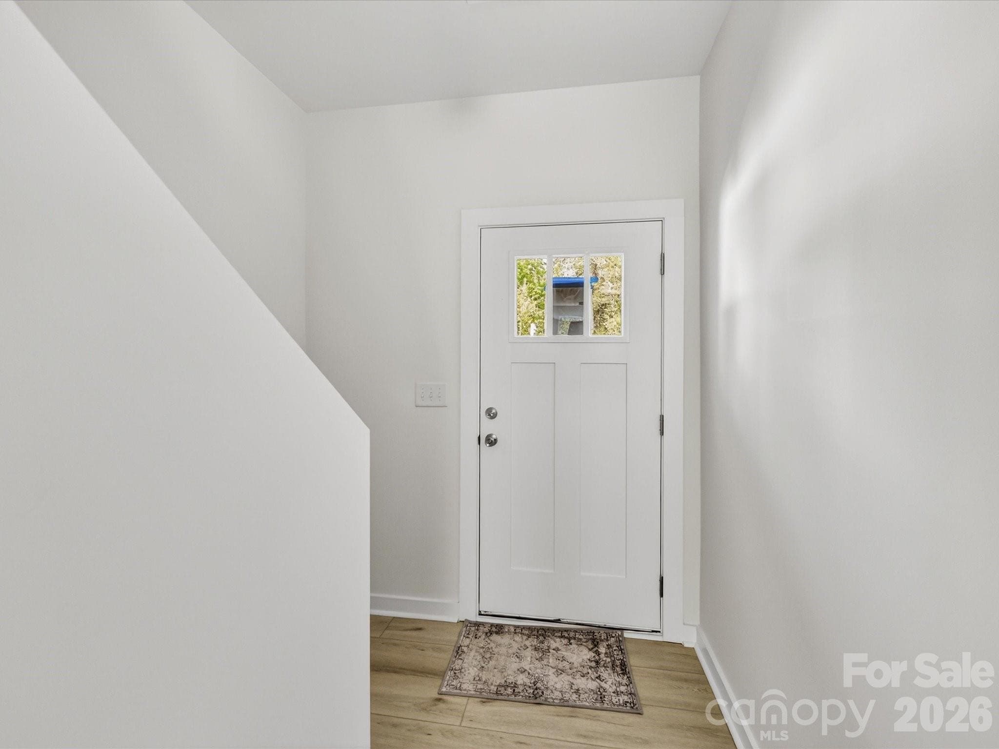 Bright and welcoming foyer featuring clean modern finishes, durable flooring, and a convenient staircase leading to the upper level. - 655 Stillgreen Lane, Charlotte