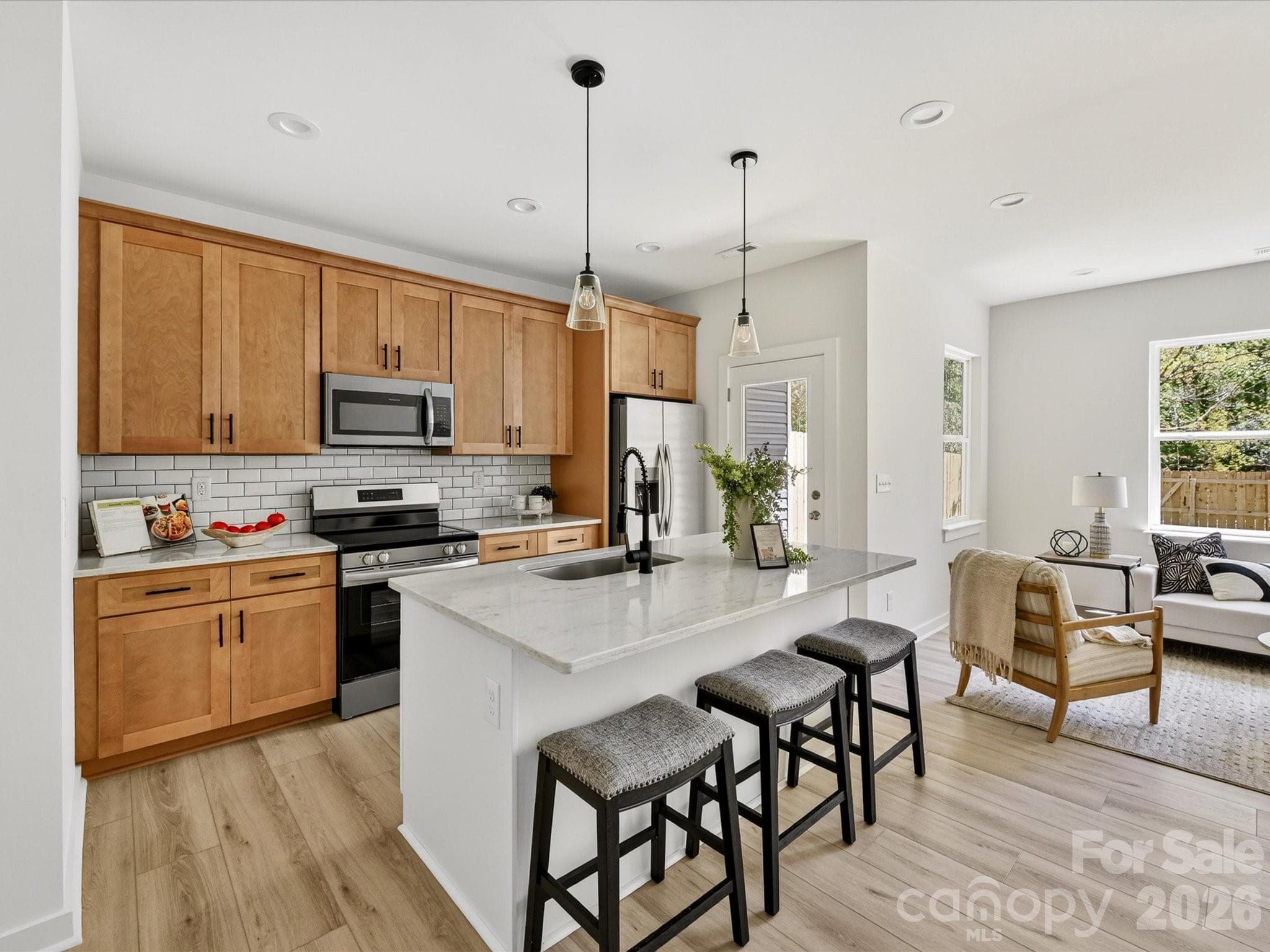 Stylish open-concept kitchen featuring granite countertops, stainless steel appliances, subway tile backsplash, and a spacious island with seating, perfect for everyday living and entertaining. - Charlotte