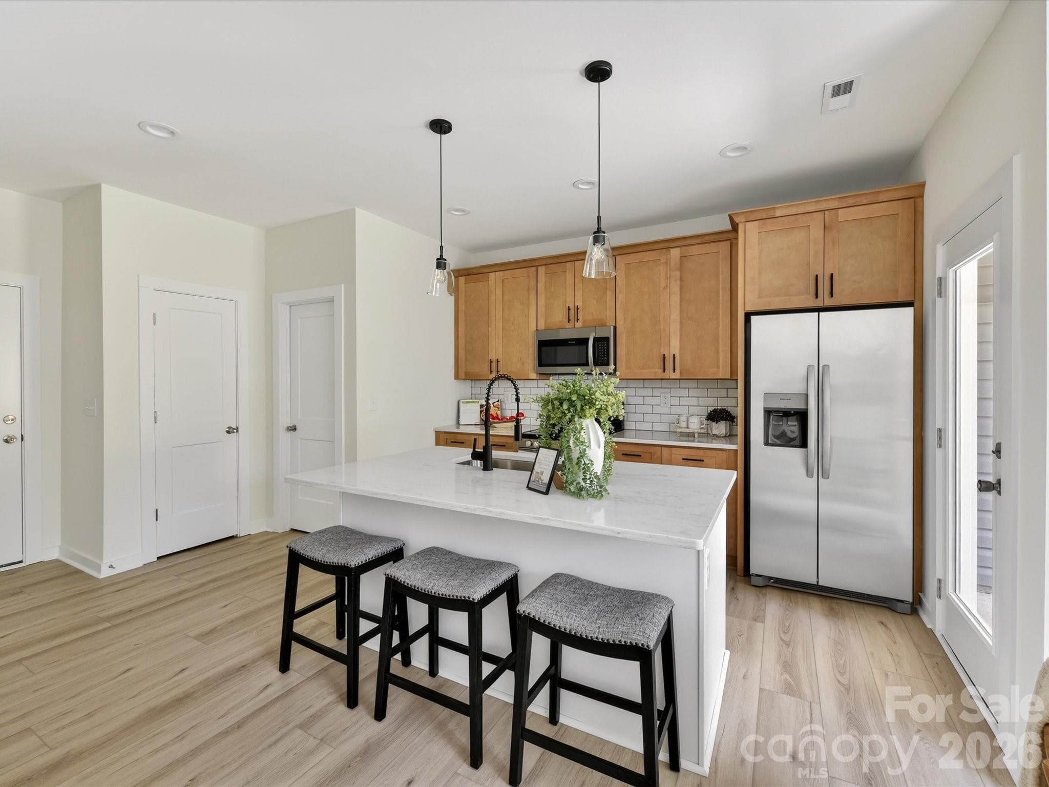 Stylish open-concept kitchen featuring granite countertops, stainless steel appliances, subway tile backsplash, and a spacious island with seating, perfect for everyday living and entertaining. - 655 Stillgreen Lane, Charlotte