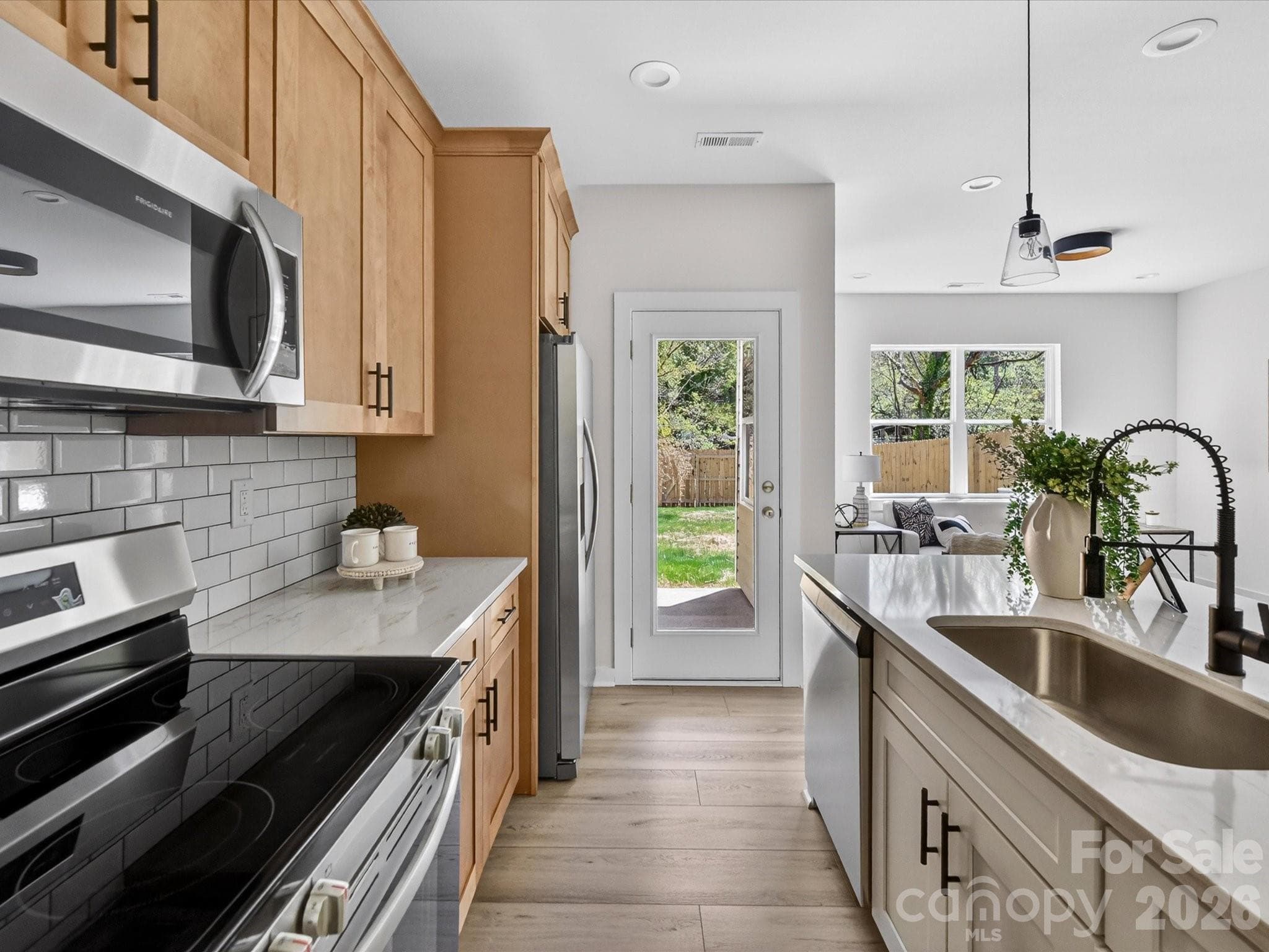 Stylish open-concept kitchen featuring granite countertops, stainless steel appliances, subway tile backsplash, and a spacious island with seating, perfect for everyday living and entertaining. - 655 Stillgreen Lane, Charlotte