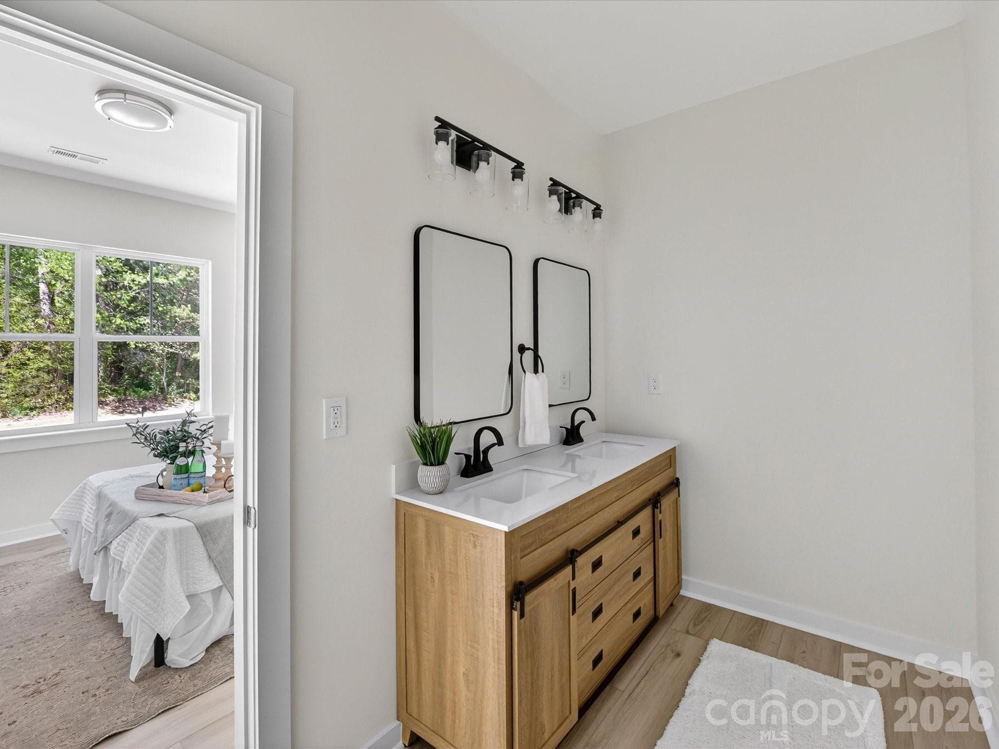 Modern primary bath vanity featuring dual sinks, sleek fixtures, and a stylish wood cabinet with ample storage. - 655 Stillgreen Lane, Charlotte
