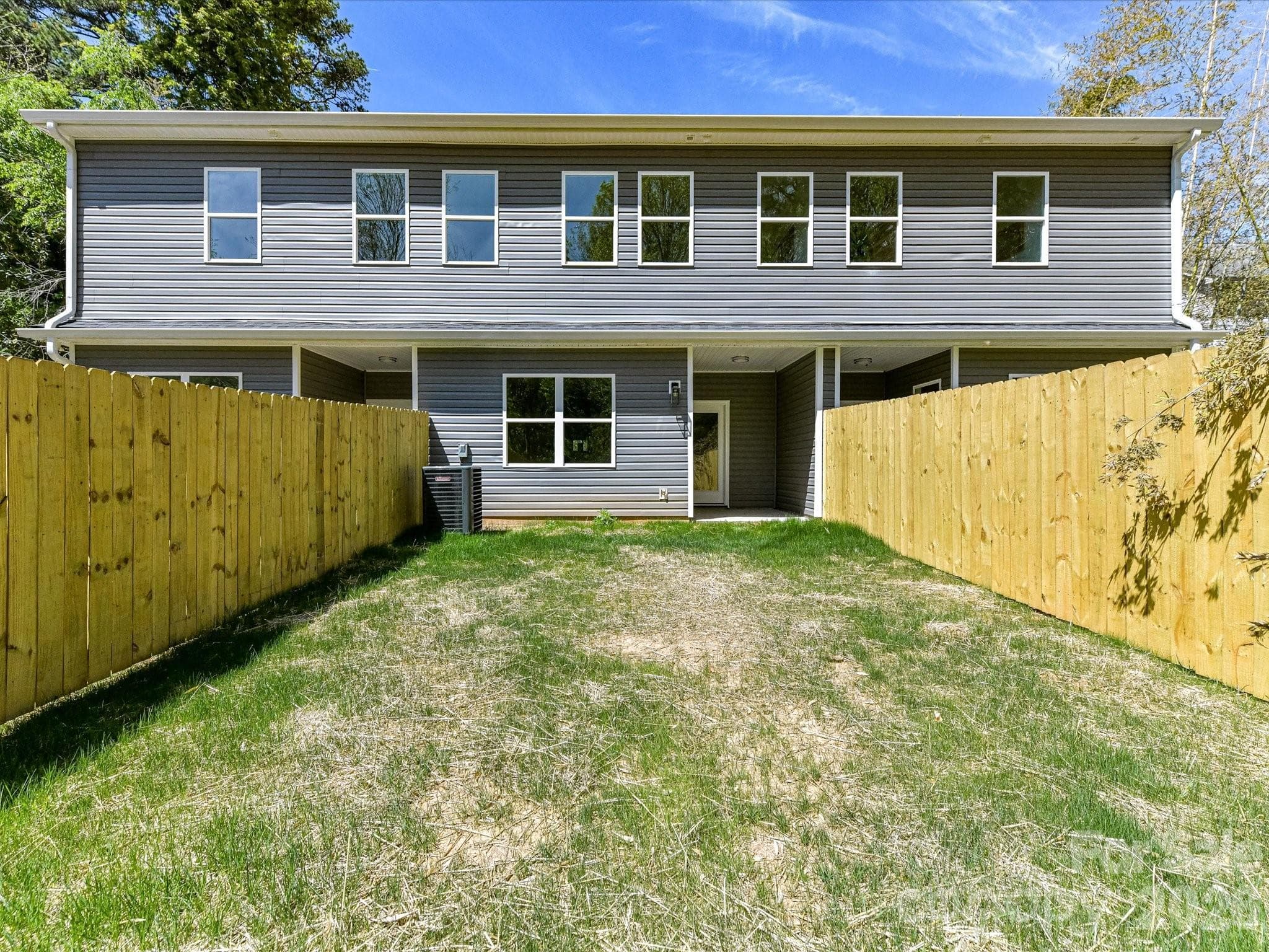 Rear exterior of the townhome featuring a covered patio and private fenced backyard, perfect for outdoor enjoyment and low-maintenance living. - 655 Stillgreen Lane, Charlotte