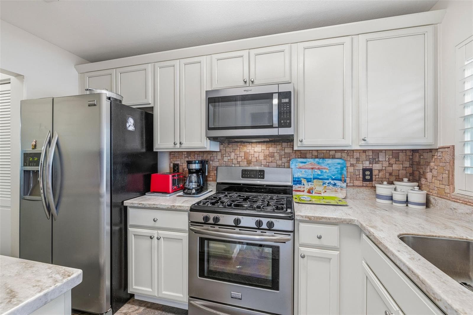 Kitchen with stainless appliances and ample storage - 5521 80TH ST N #212, ST PETERSBURG