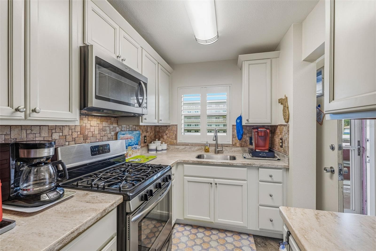 Galley kitchen layout with bright lighting - 5521 80TH ST N #212, ST PETERSBURG