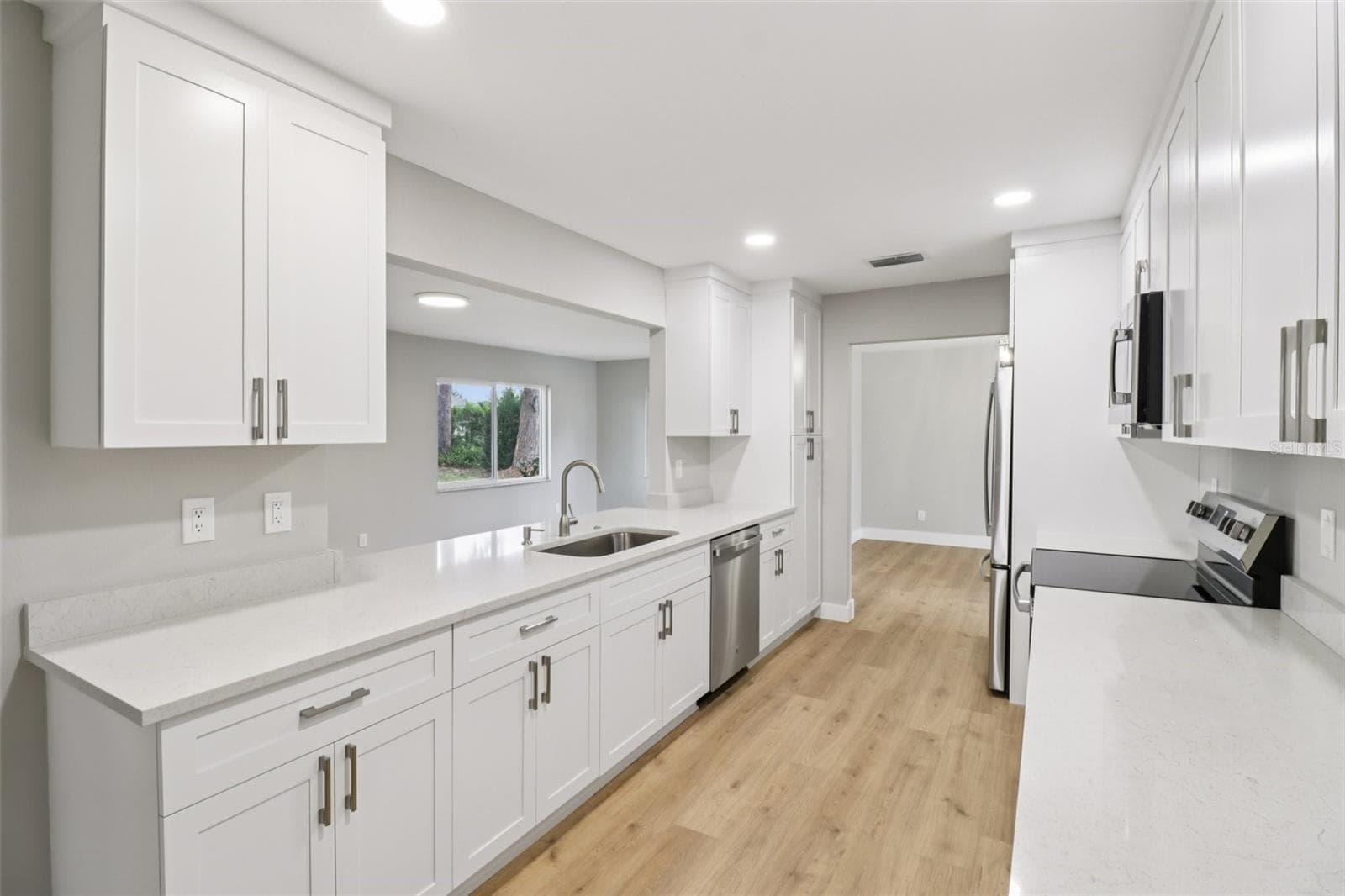 The FULLY RENOVATED KITCHEN is fresh and modern, featuring sleek stone countertops, STAINLESS STEEL APPLIANCES, ample cabinet storage, and a breakfast bar passthrough that keeps the home chef connected to the family room. - 1412 DIGARMO TER, DELTONA