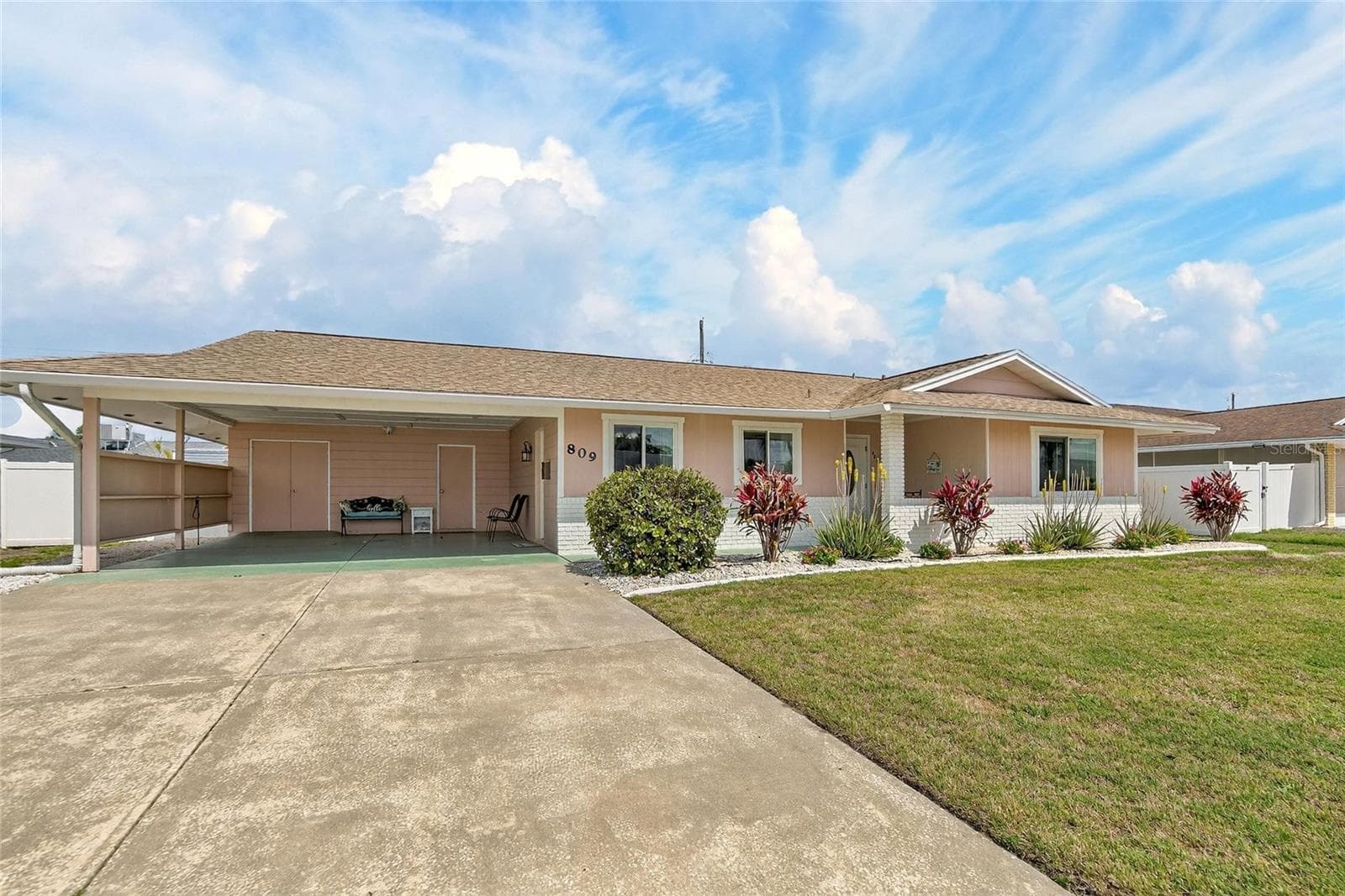 Carport with double doors leading to golf cart storage and single door to laundry room - 809 OAKMONT AVE, SUN CITY CENTER
