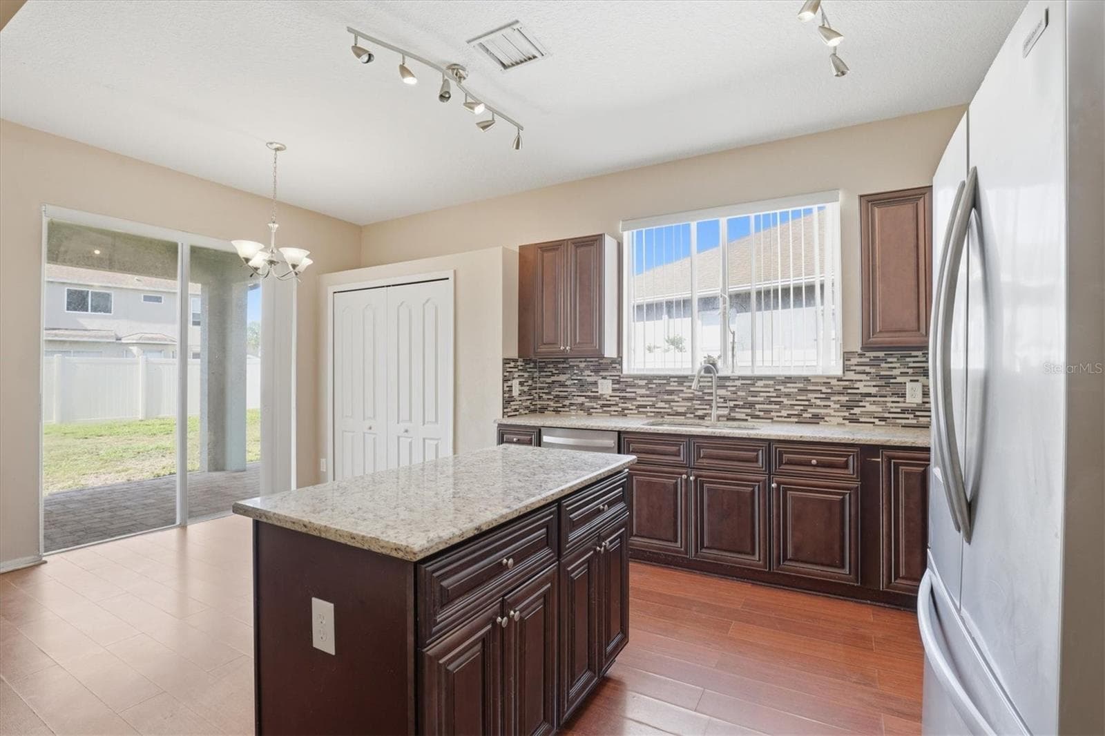 Open Kitchen with Granite Countertops, Center Island, Tile Backsplash, and Stainless Steel Appliances - 3036 GIANNA WAY, LAND O LAKES