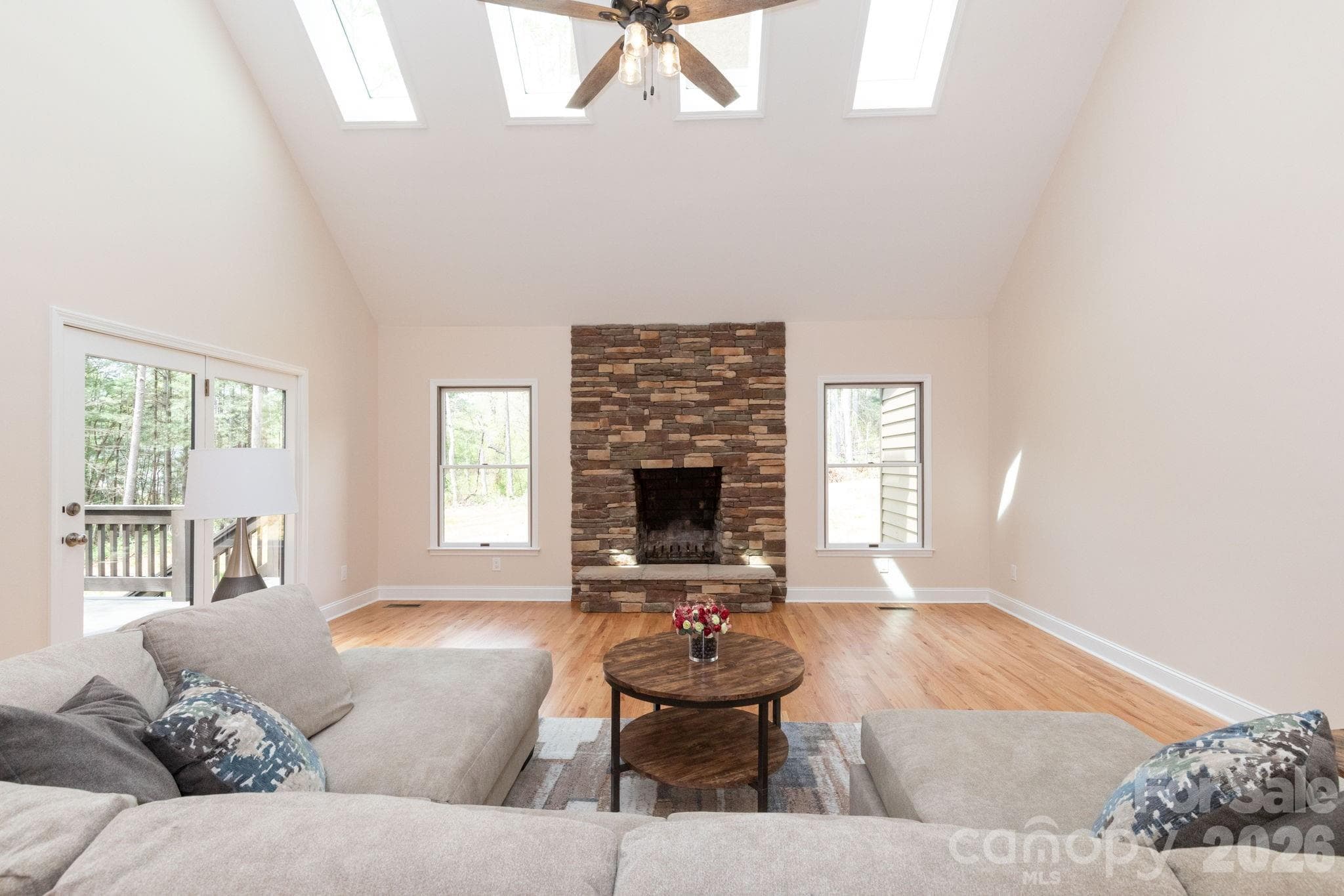 Stunning living room with vaulted ceilings, skylights, and a beautiful stone fireplace as the focal point. - Fletcher