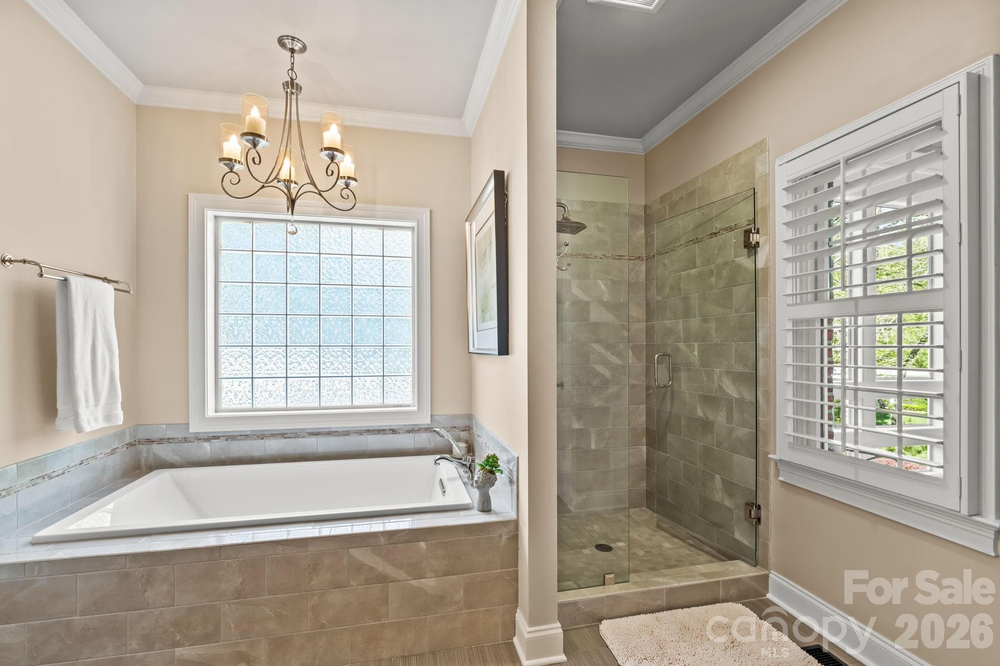 Soaking tub and walk in tiled shower with glass block window and plantation shutters for privacy - Lewisville