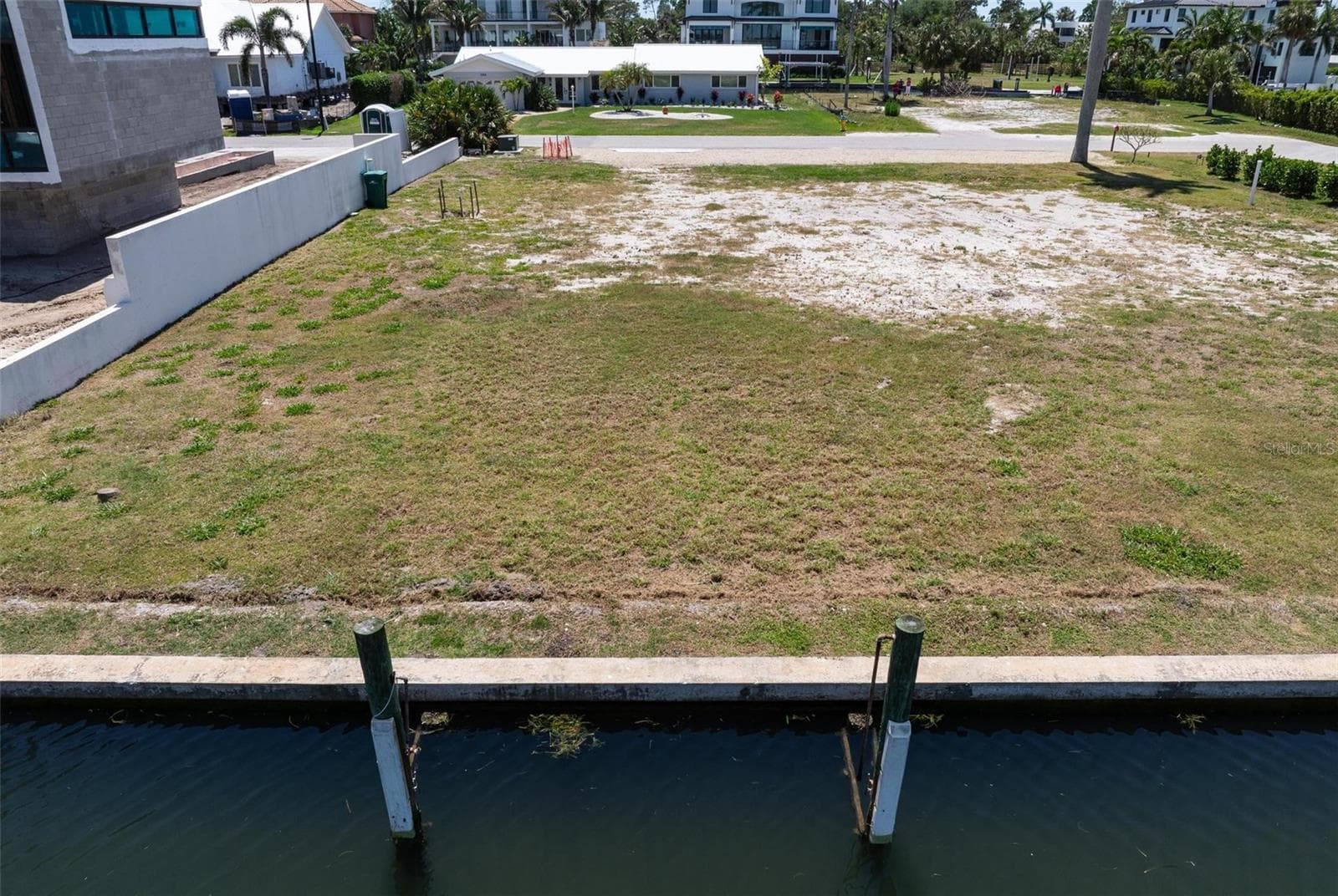 View from canal onto over quarter acre vacant lot and palm tree to right front of lot. - 581 ROUNTREE DR, LONGBOAT KEY