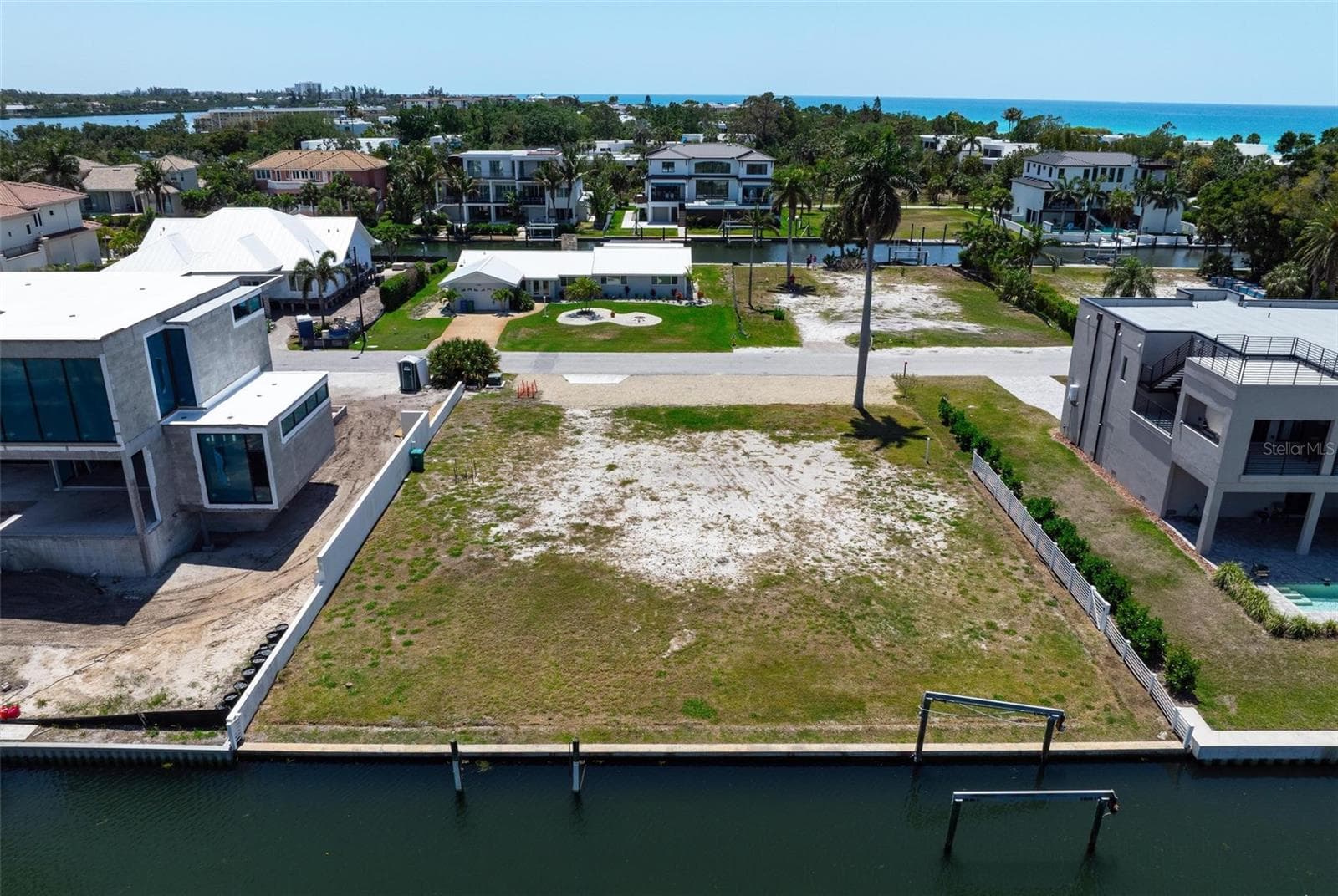 Drone view of deep water canal front vacant lot with Gulf views beyond. Brand new mansions on either side of the lot. - 581 ROUNTREE DR, LONGBOAT KEY