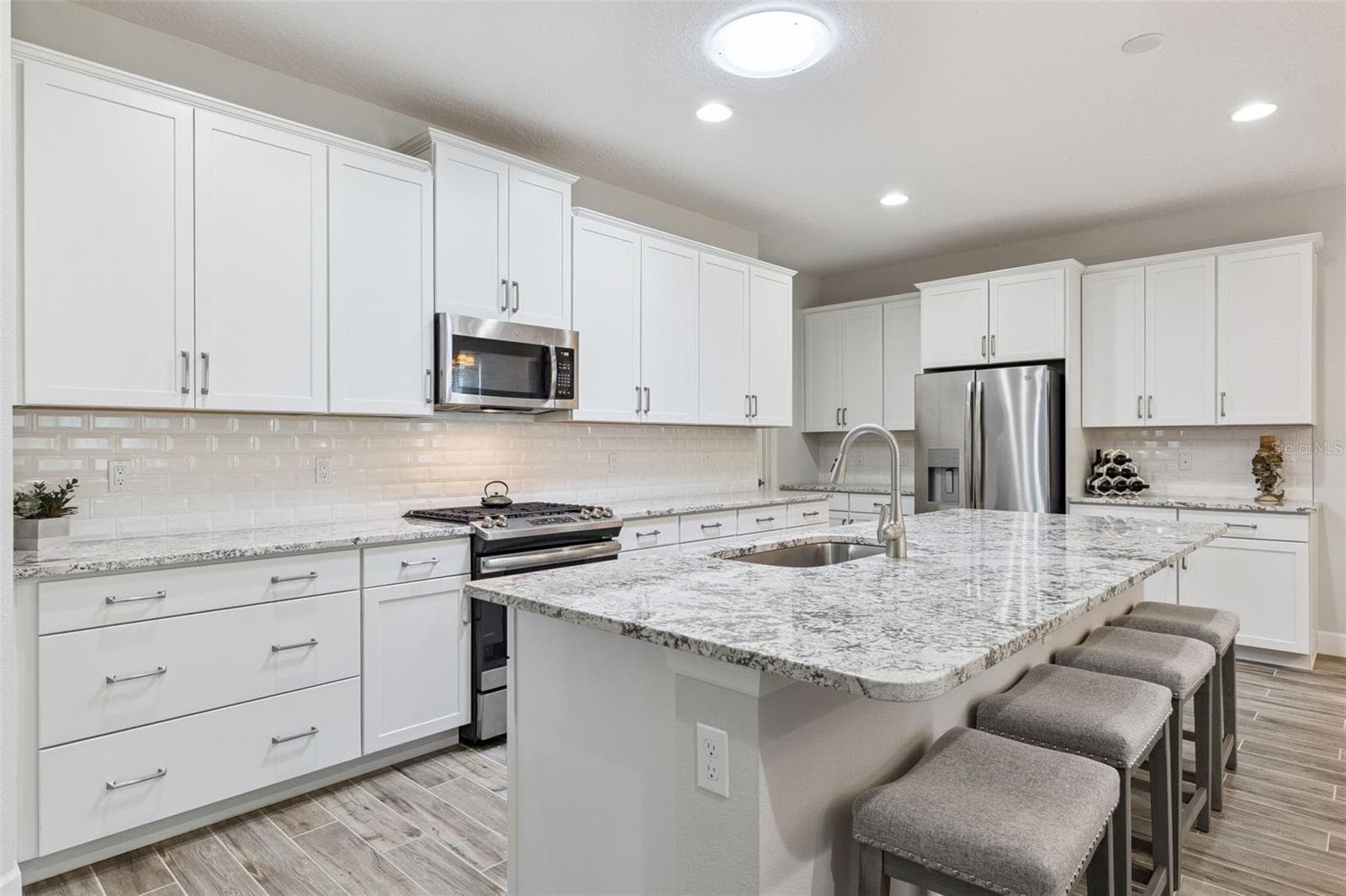 The kitchen features lovely white cabinets, stunning granite, stainless steel appliances,  large island, and a Solatube® Skylight - 1157 AVERY MEADOWS WAY, DELAND