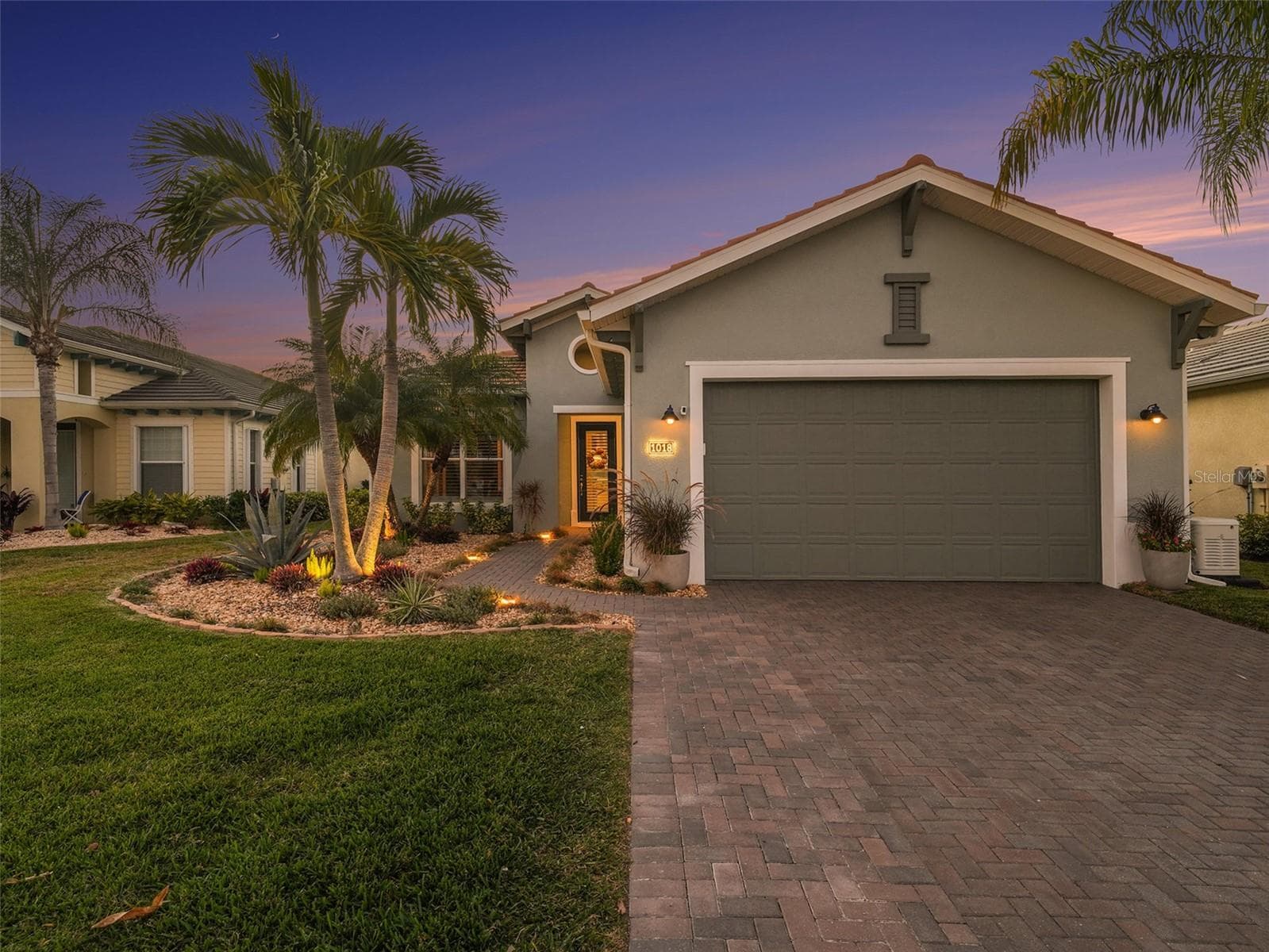 Inviting front exterior with tropical landscaping, a paver driveway, and impressive curb appeal. - 1018 OVERLOOK CT, BRADENTON