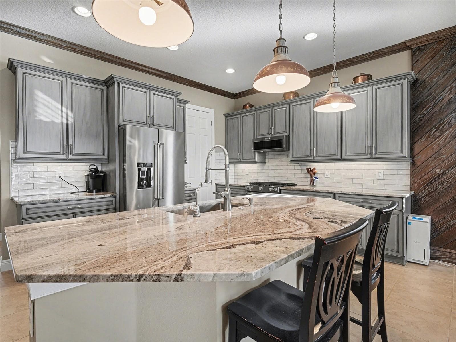 Elegant kitchen with expansive island seating, designer lighting, and seamless flow into the main living areas. - 1018 OVERLOOK CT, BRADENTON