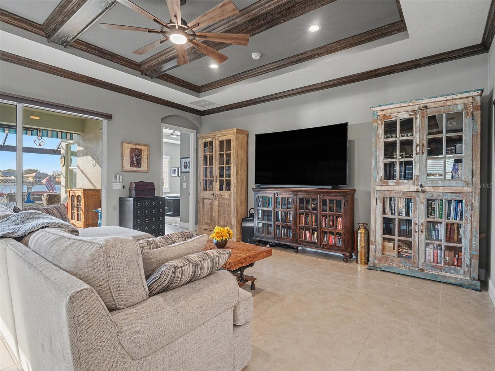 Open concept living room with built in features, tray ceiling detail, and easy access to the kitchen and outdoor living spaces. - 1018 OVERLOOK CT, BRADENTON