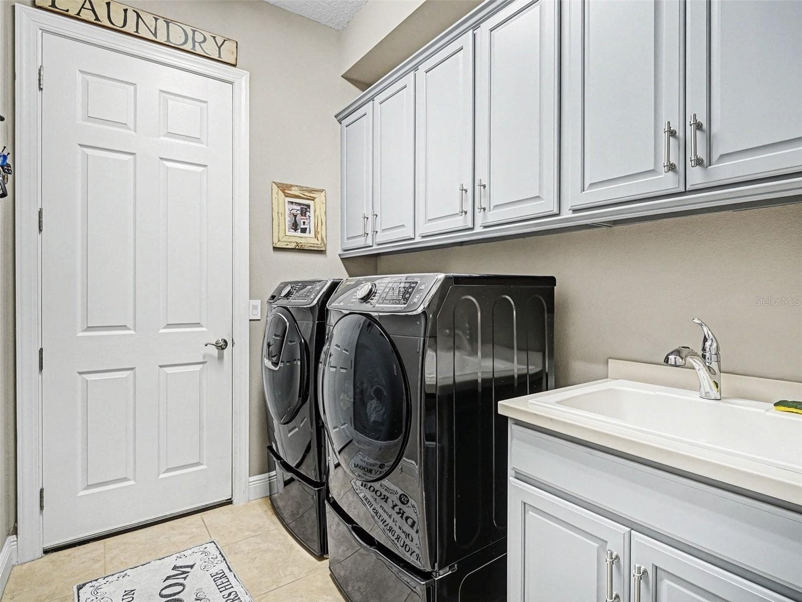 Spacious laundry room with upper cabinetry, utility sink, and plenty of room for storage and organization. - 1018 OVERLOOK CT, BRADENTON