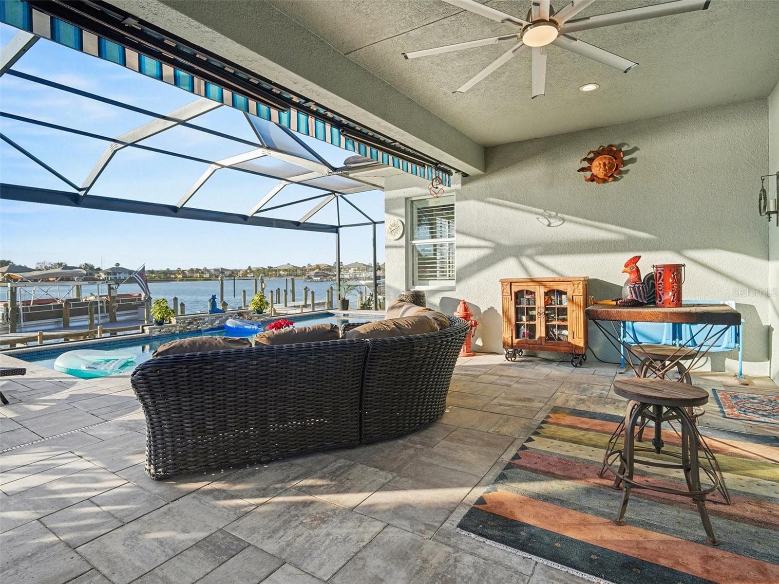 Covered waterfront outdoor living area with lounge seating, ceiling fans, and sweeping views for effortless entertaining. - 1018 OVERLOOK CT, BRADENTON