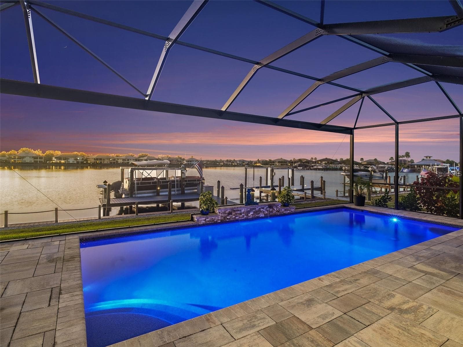 Twilight view of the screened pool and lanai showcasing a stunning outdoor retreat with glowing water and sunset skies. - 1018 OVERLOOK CT, BRADENTON
