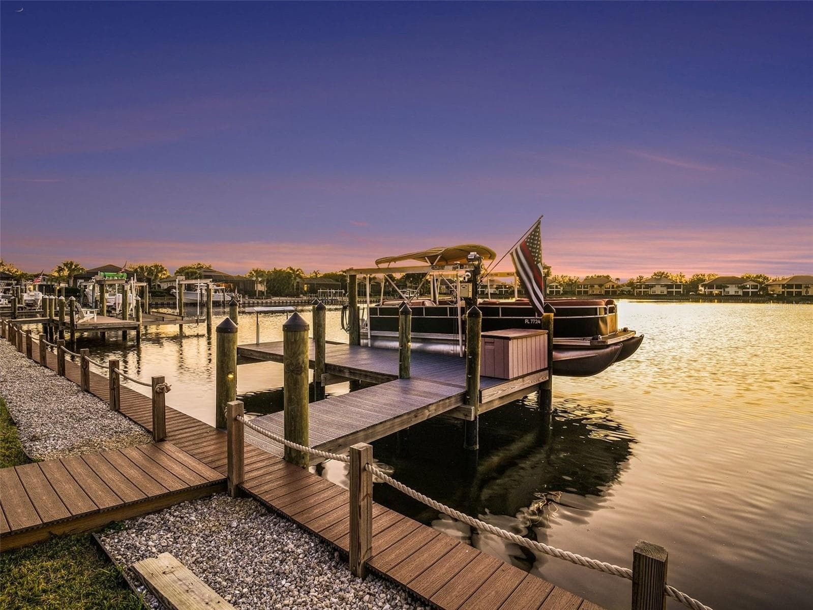 Private dock and boat lift at sunset with wide water views and direct boating access for the ultimate waterfront lifestyle. - 1018 OVERLOOK CT, BRADENTON