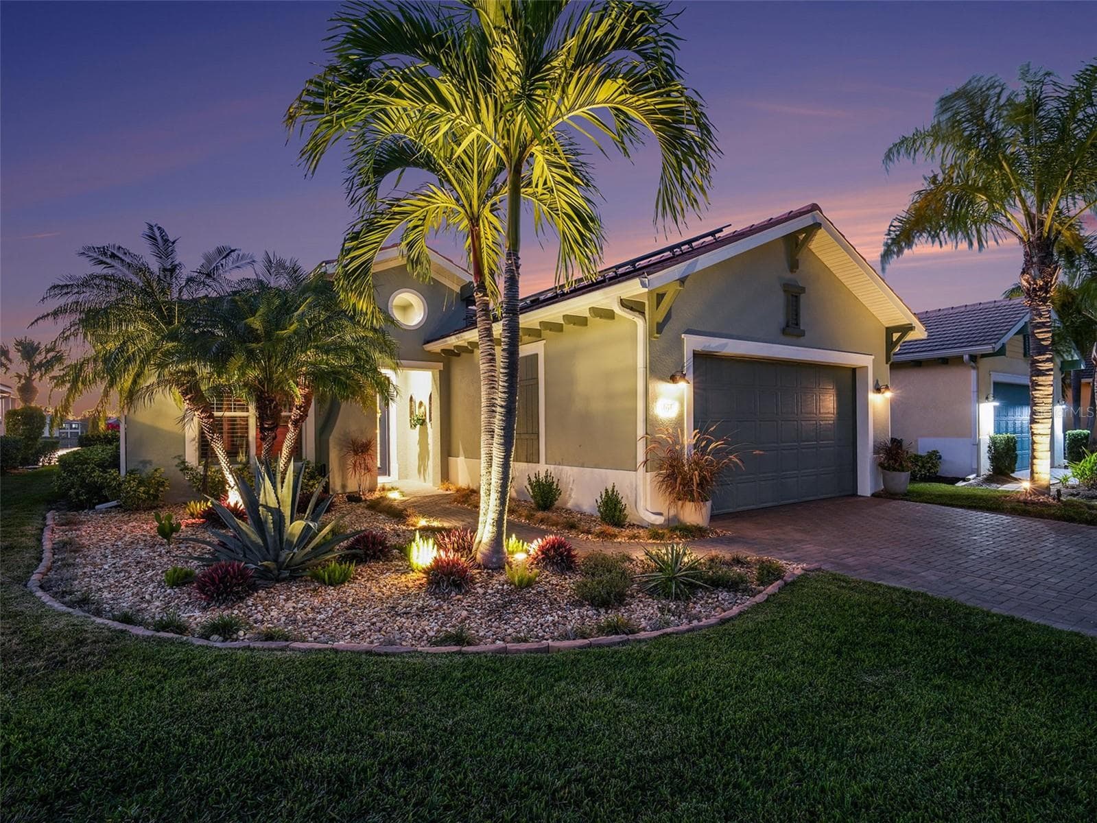 Evening exterior view featuring illuminated landscaping and elegant architectural details for a striking first impression. - 1018 OVERLOOK CT, BRADENTON