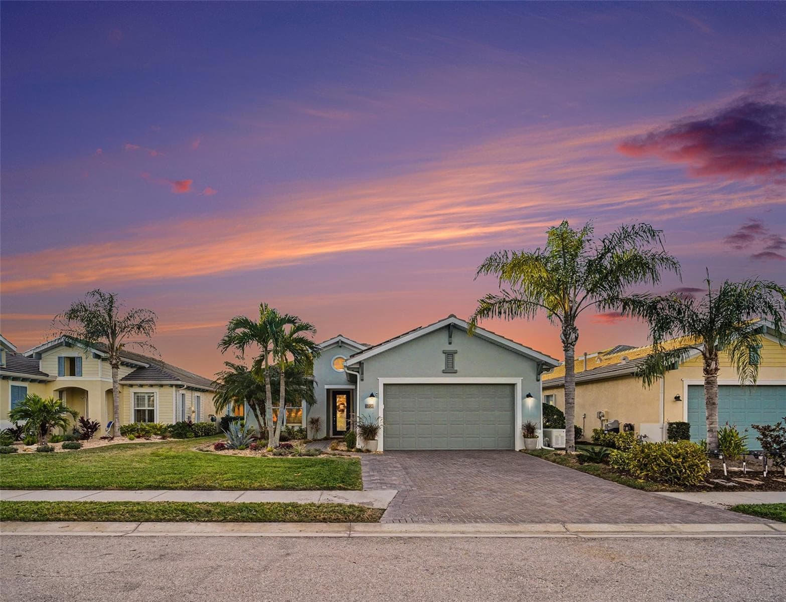 Front exterior at sunset with tropical landscaping, warm evening light, and standout visual appeal. - 1018 OVERLOOK CT, BRADENTON