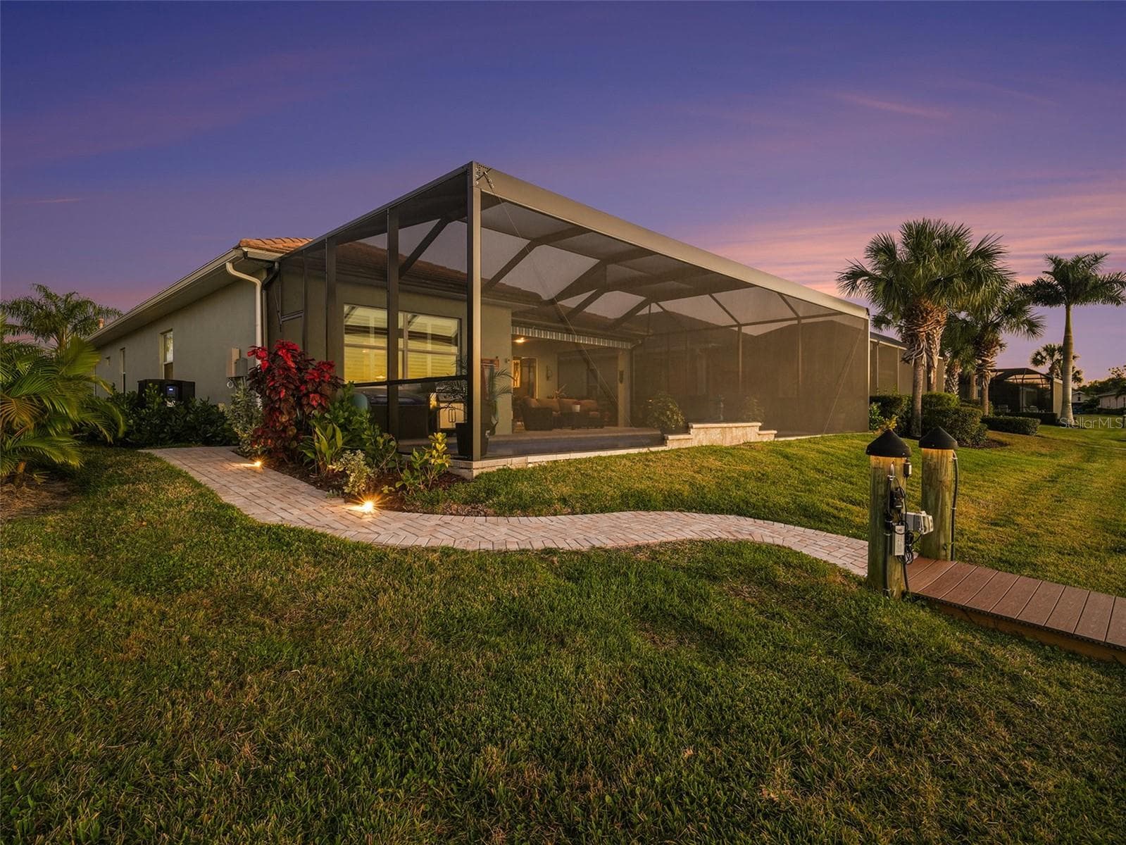 Twilight exterior view highlighting the screened lanai, manicured landscaping, and impressive outdoor living design. - 1018 OVERLOOK CT, BRADENTON