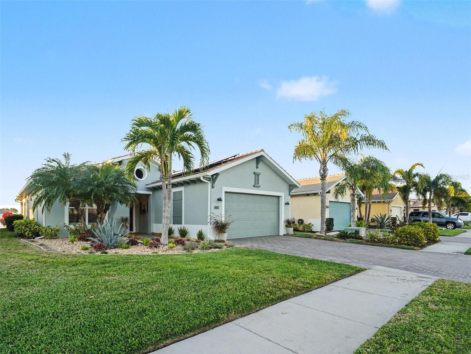 Front exterior with lush lawn, tropical landscaping, and a welcoming entrance that enhances everyday curb appeal. - 1018 OVERLOOK CT, BRADENTON