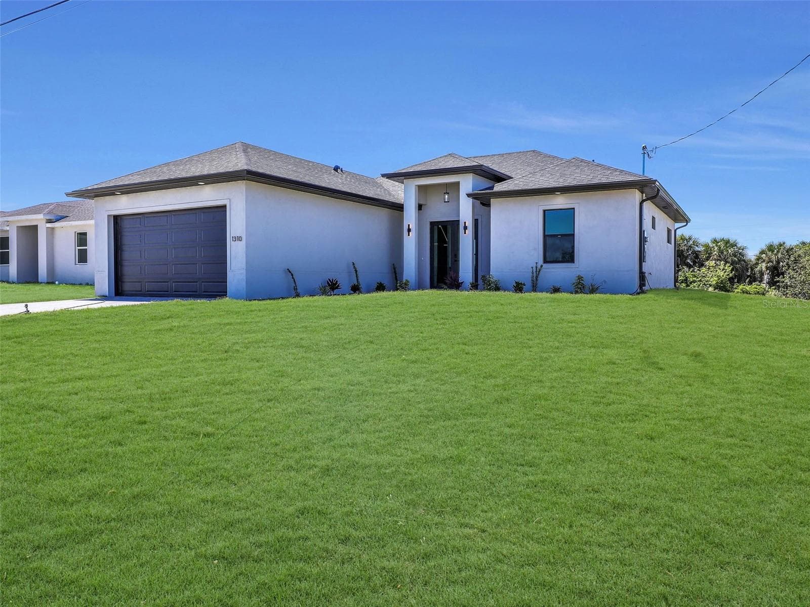 Contemporary stucco exterior with dark trimaccents the color of the grass has been virtually enhanced - 1310 NW 11TH TER, CAPE CORAL