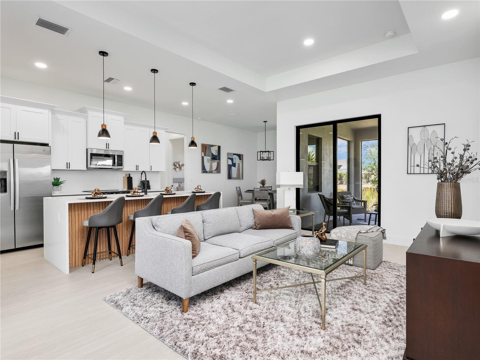 Open-concept living space featuring a kitchen island with seating, stainless steel appliances, and wood-finish flooring photos used from another listing to show what it would look like with furniture - 1310 NW 11TH TER, CAPE CORAL