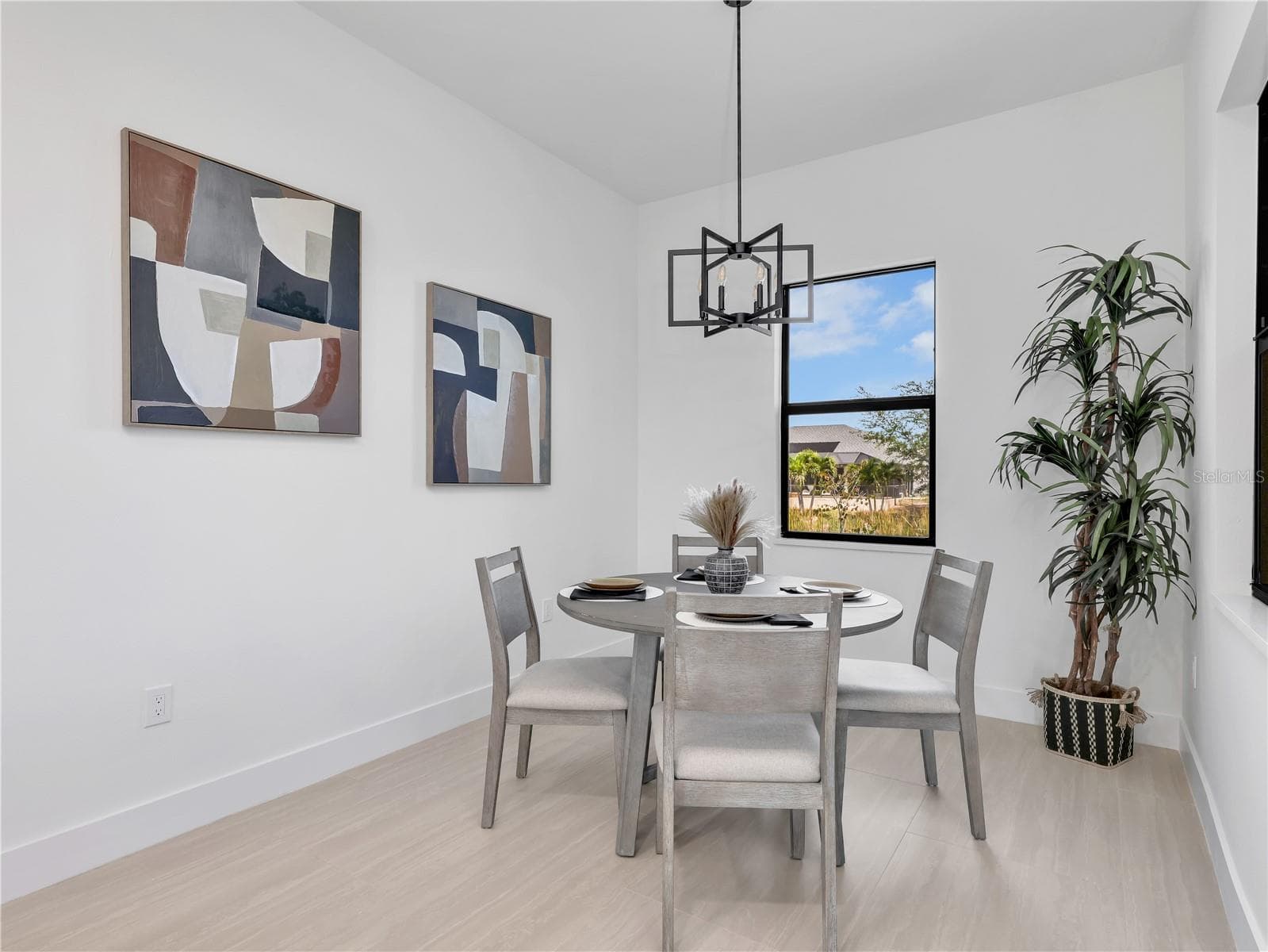 Dining area featuring light wood-finish flooring and a contemporary black geometric chandelier photos used from another listing to show what it would look like with furniture - 1310 NW 11TH TER, CAPE CORAL