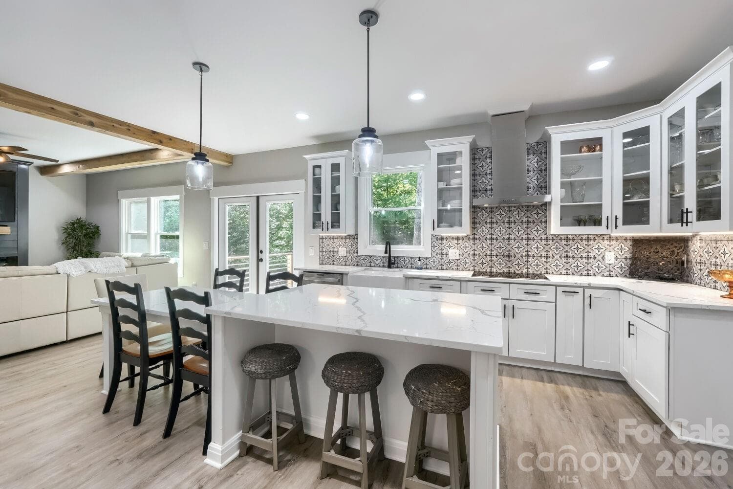 Chef's kitchen showcasing quartz countertops, white shaker cabinetry, farmhouse sink, black hardware, stainless dishwasher, and bold encaustic tile backsplash. - Albemarle