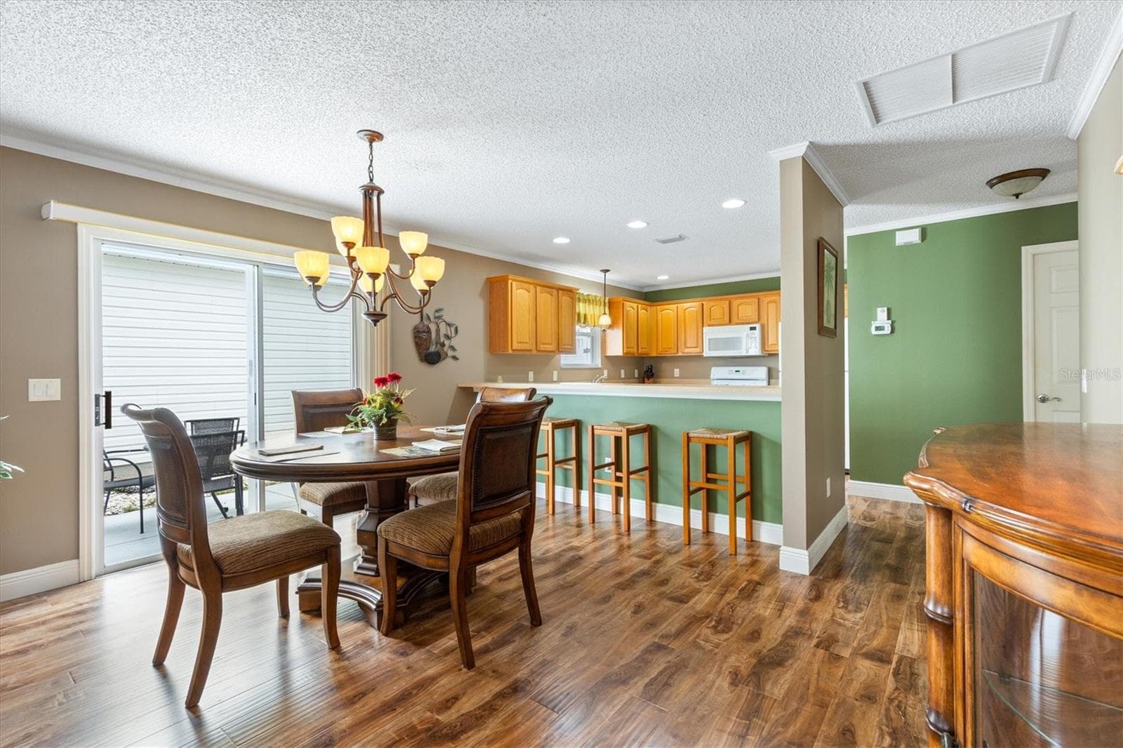 DINING ROOM LOOKING TOWARDS KITCHEN AND OUTDOOR SIDE LANAI WITH OUTDOOR SEATING AND A GRILL - 979 SMYRNA ST, THE VILLAGES