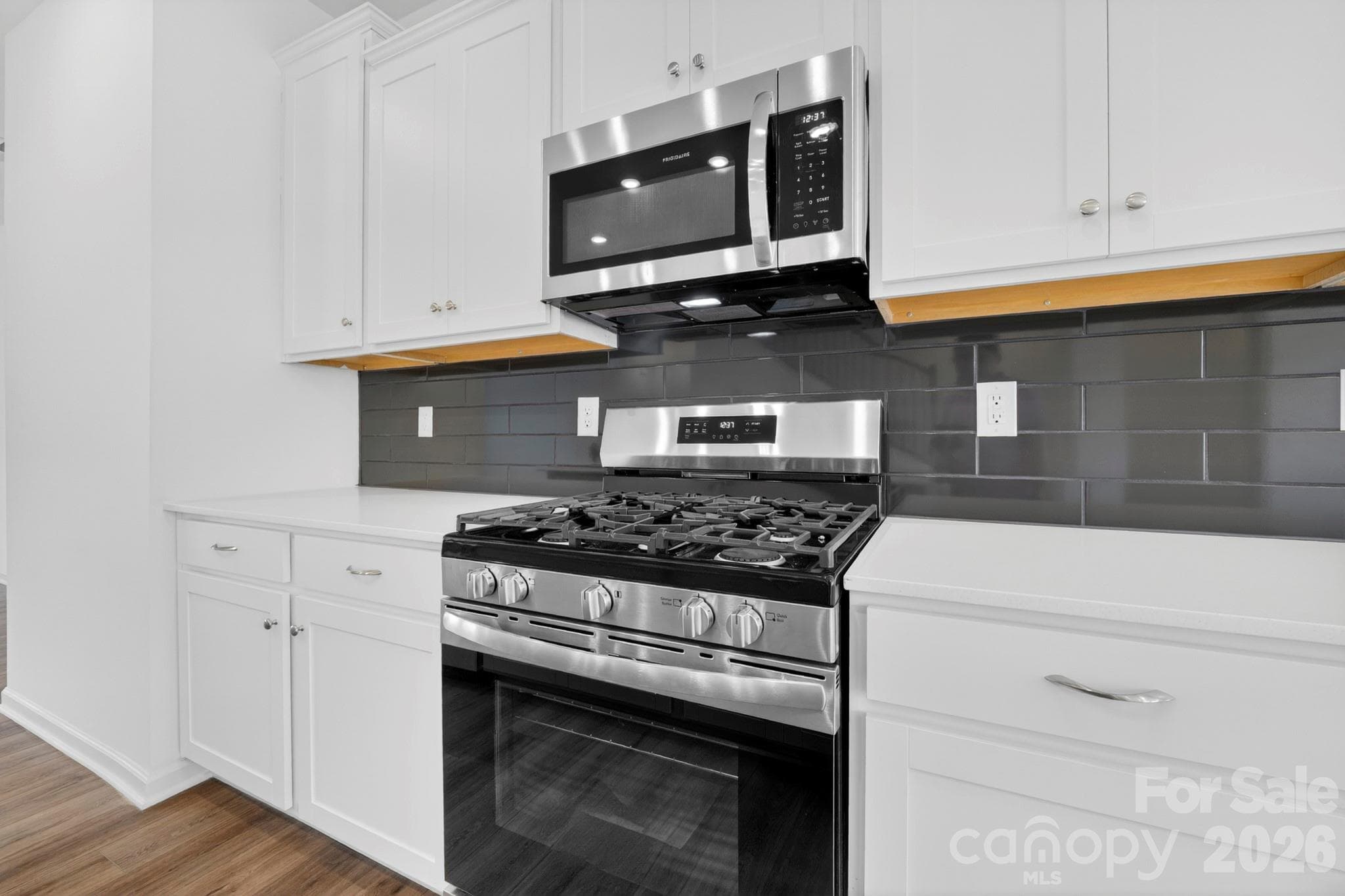 Clean, elegant white cabinets and 5-burner gas range with vented microwave - Mooresville