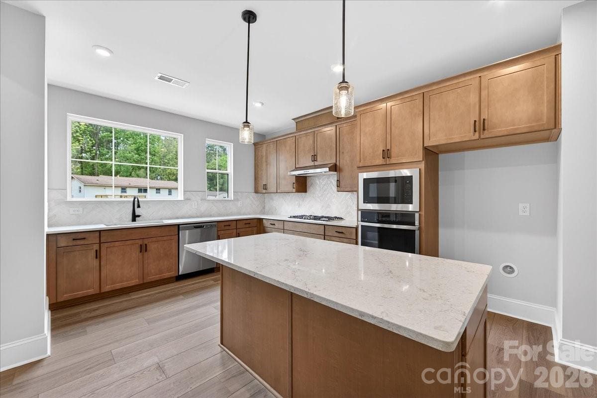 Gourmet kitchen with warm brown cabinets and white quartz countertops - 420 Old Town Village Road, Waxhaw