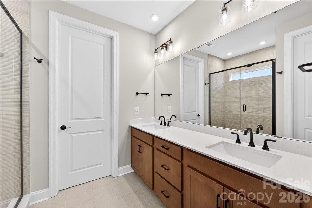 Dual vanity primary bathroom with warm brown cabinets and white quartz countertops - 420 Old Town Village Road, Waxhaw